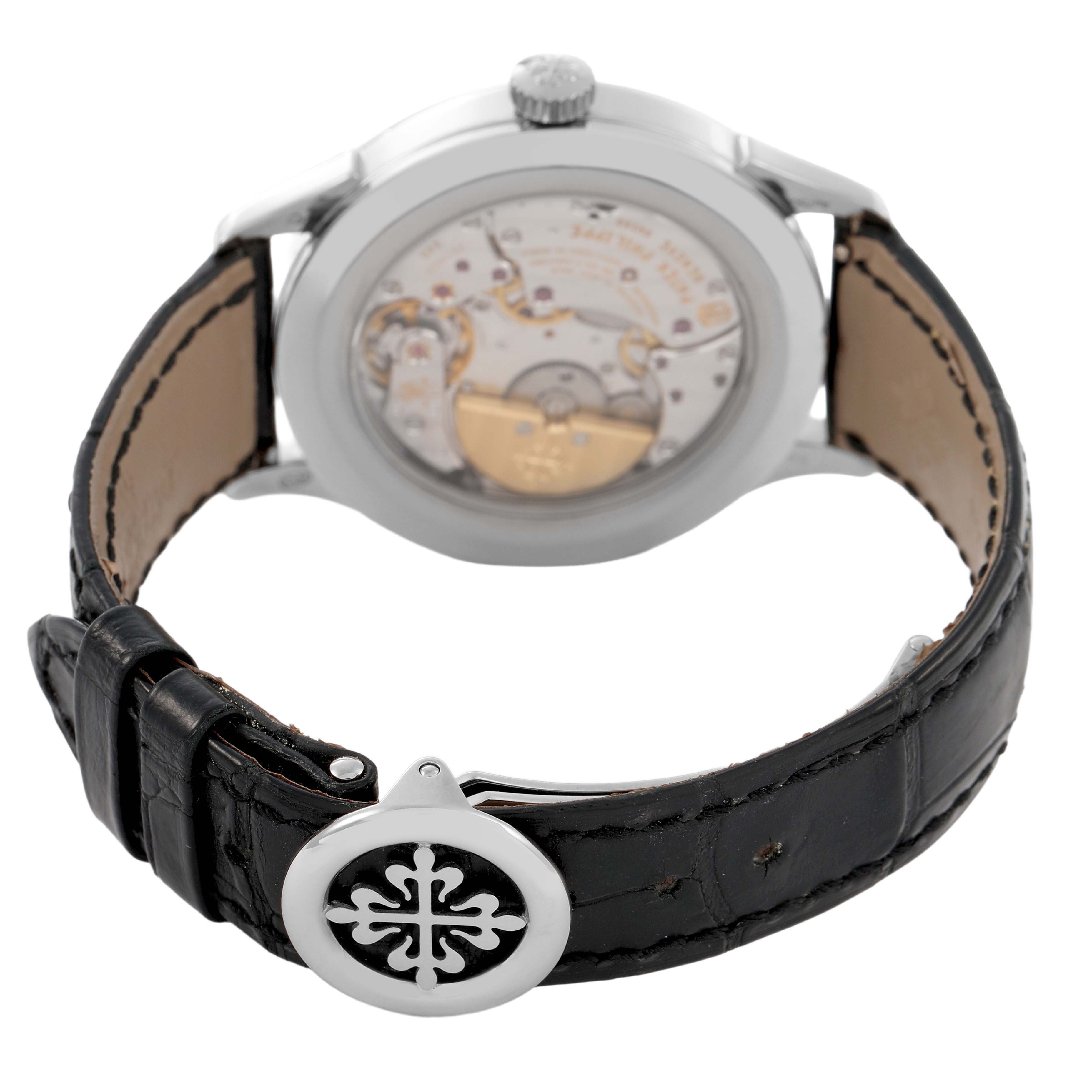 The image shows the back of a Patek Philippe Complications 5230G-001 Men's White Gold Grey Dial watch, highlighting the movement and a clasp with the brand emblem.
