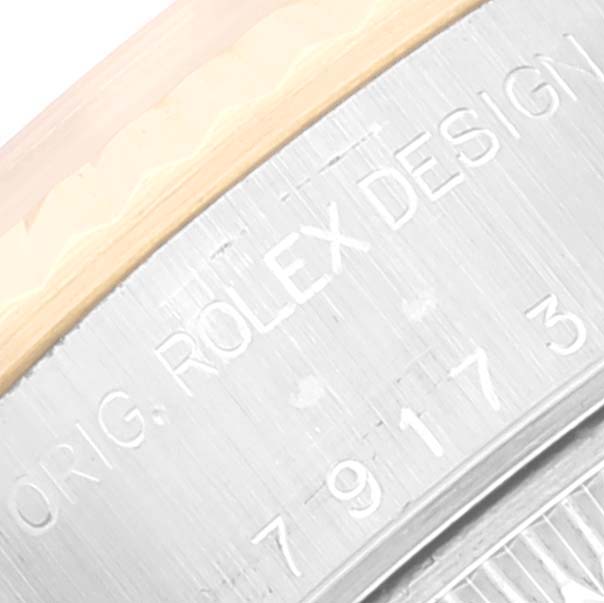The image shows a close-up of the engraved side of a Rolex Datejust 79173 Women's Steel and Gold (two tone) White Dial 79173 Women's Steel and Gold (two tone) White Dial watch case, specifically displaying part of the "Rolex Design" engraving.