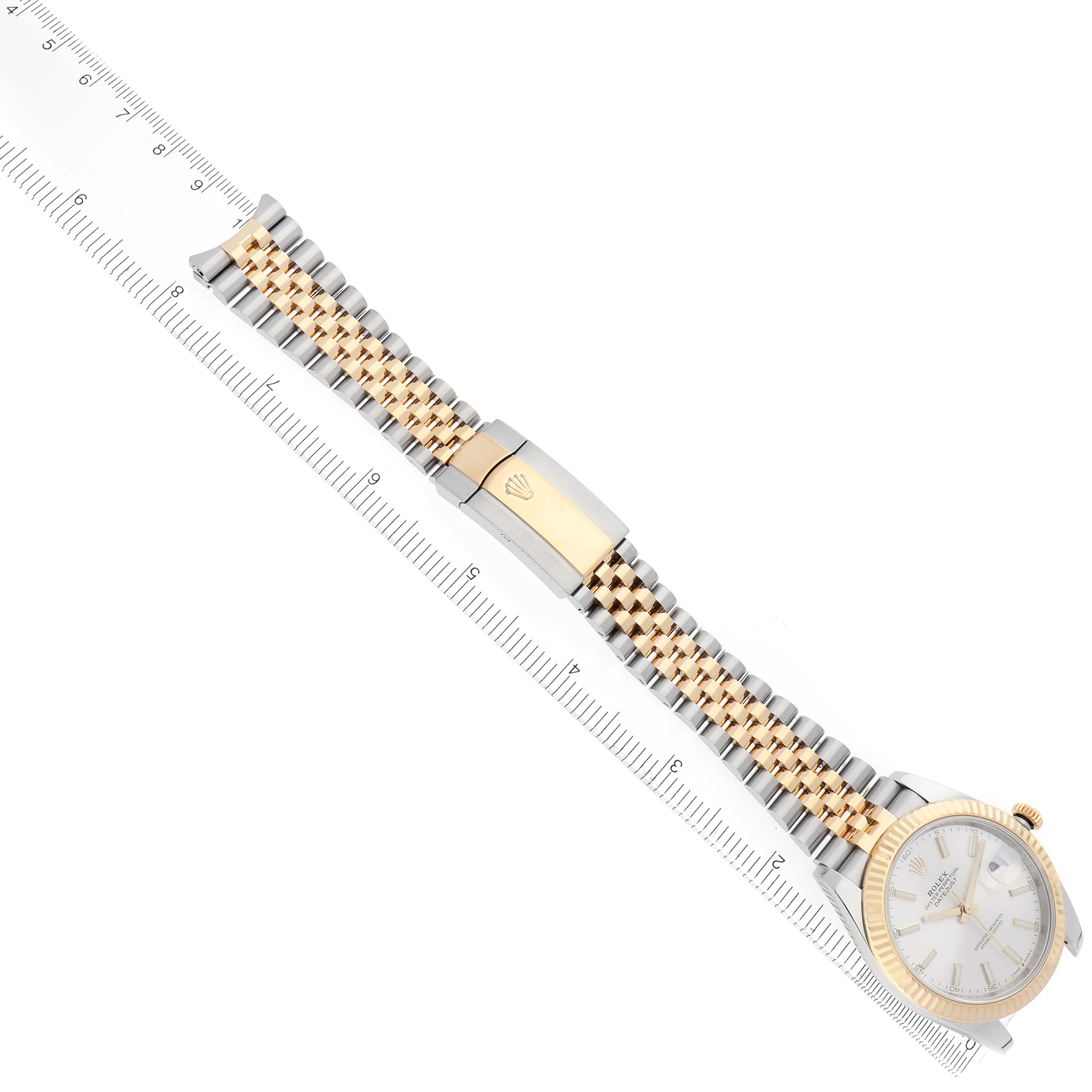 The image shows a Rolex Datejust 41 126333 Men's Steel and Gold (two tone) Silver Dial watch laid flat, displaying the dial, bracelet, and clasp at a diagonal angle next to a ruler.