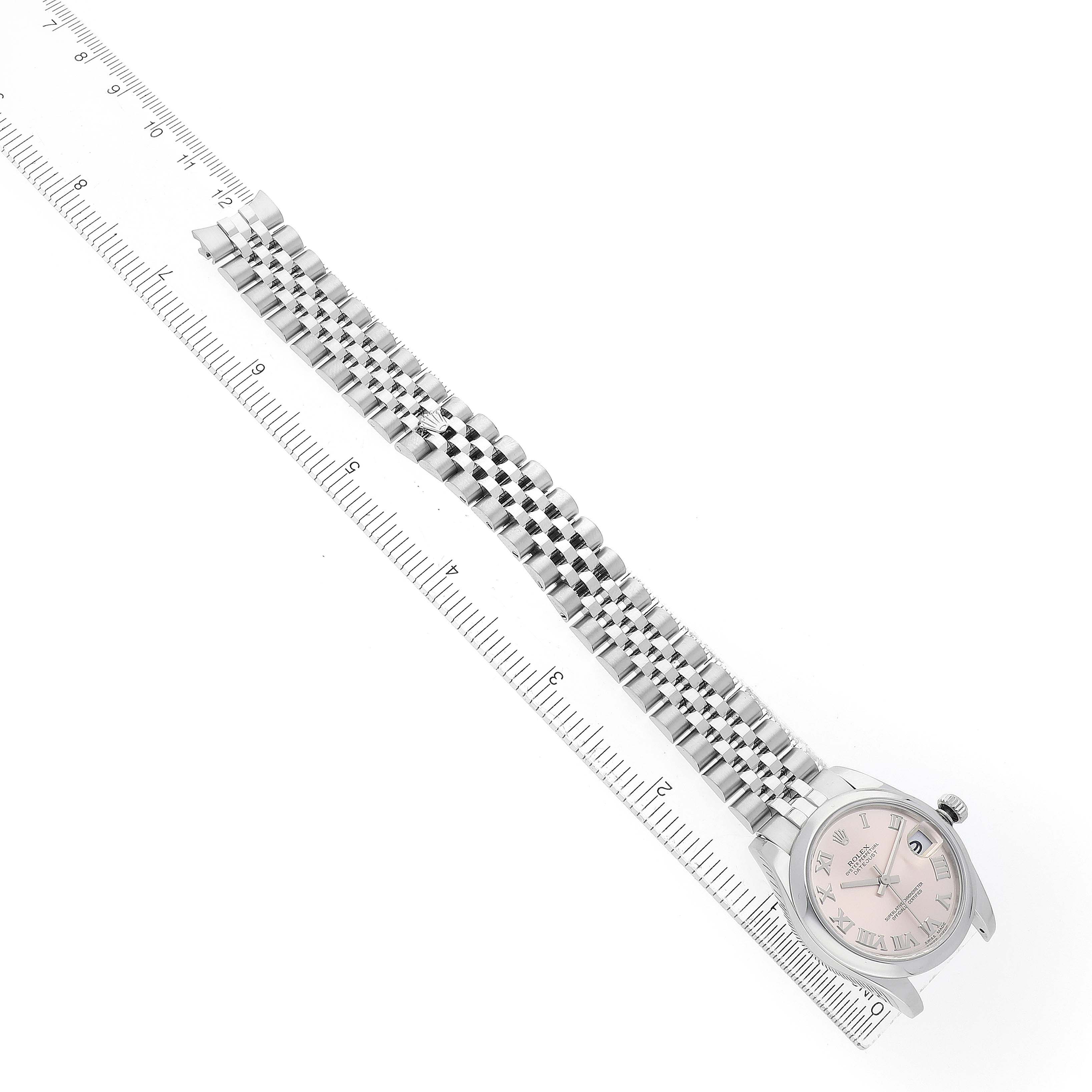 The Rolex Datejust 178240 Women's Stainless Steel Pink Dial watch is shown from an overhead angle, displaying the face, bezel, and bracelet alongside a ruler.