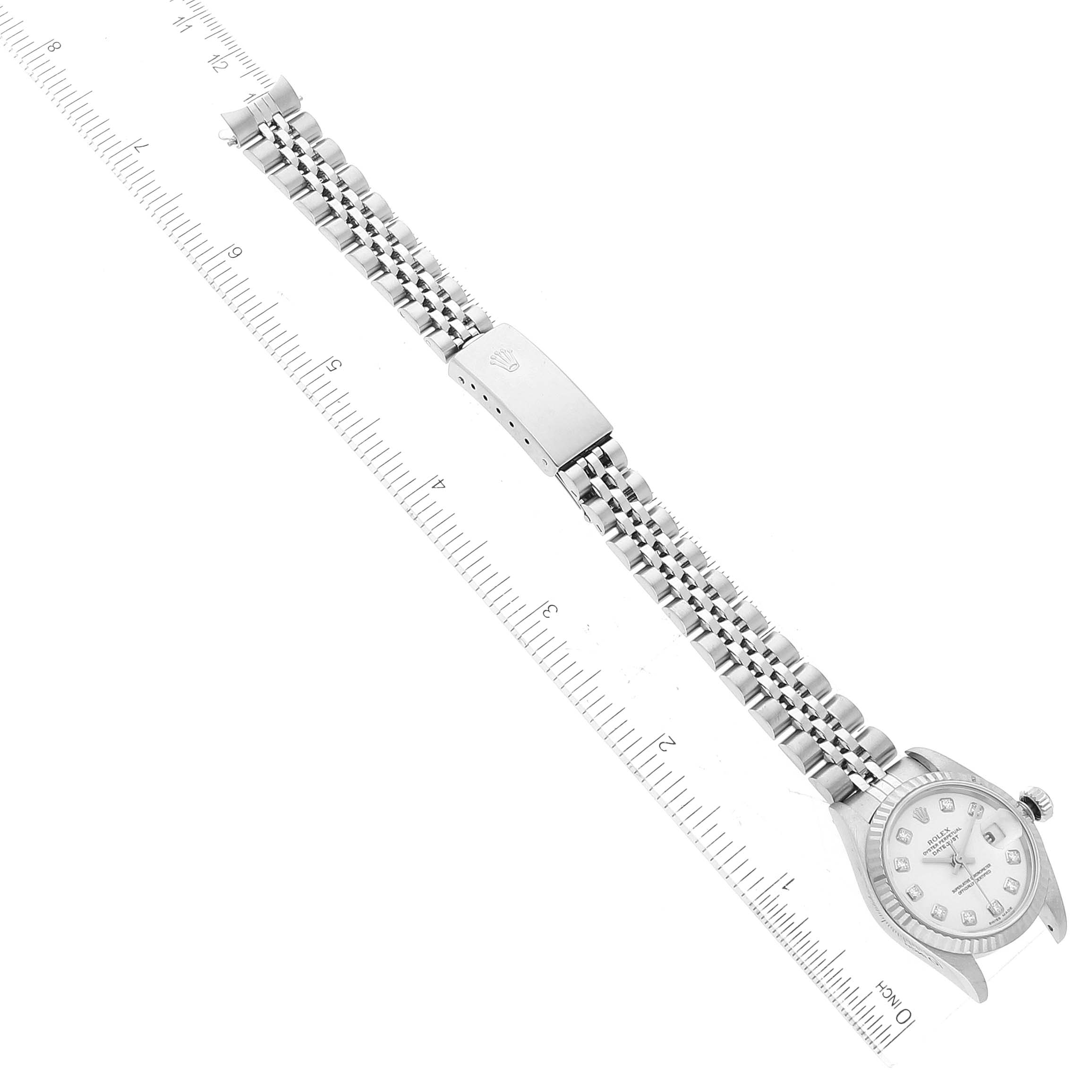 The image shows a Rolex Datejust 79174 Women's Stainless Steel White Dial 79174 Women's Stainless Steel White Dial watch laid flat alongside a ruler, displaying the watch face, bracelet, and clasp.