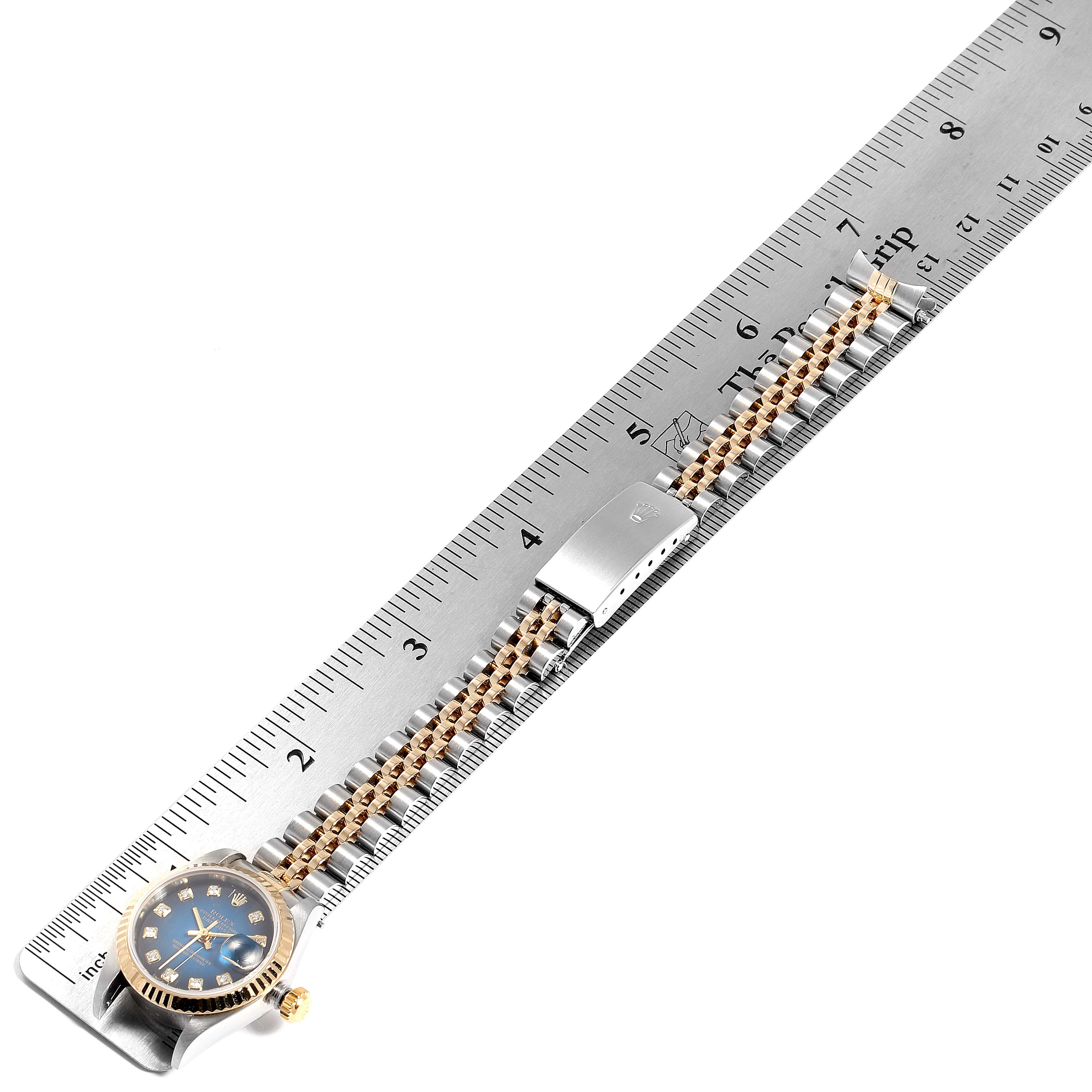 The Rolex Datejust 79173 Women's Stainless Steel Blue Dial 79173 Women's Stainless Steel Blue Dial watch is shown flat against a ruler, highlighting the watch's face, bracelet, and clasp.
