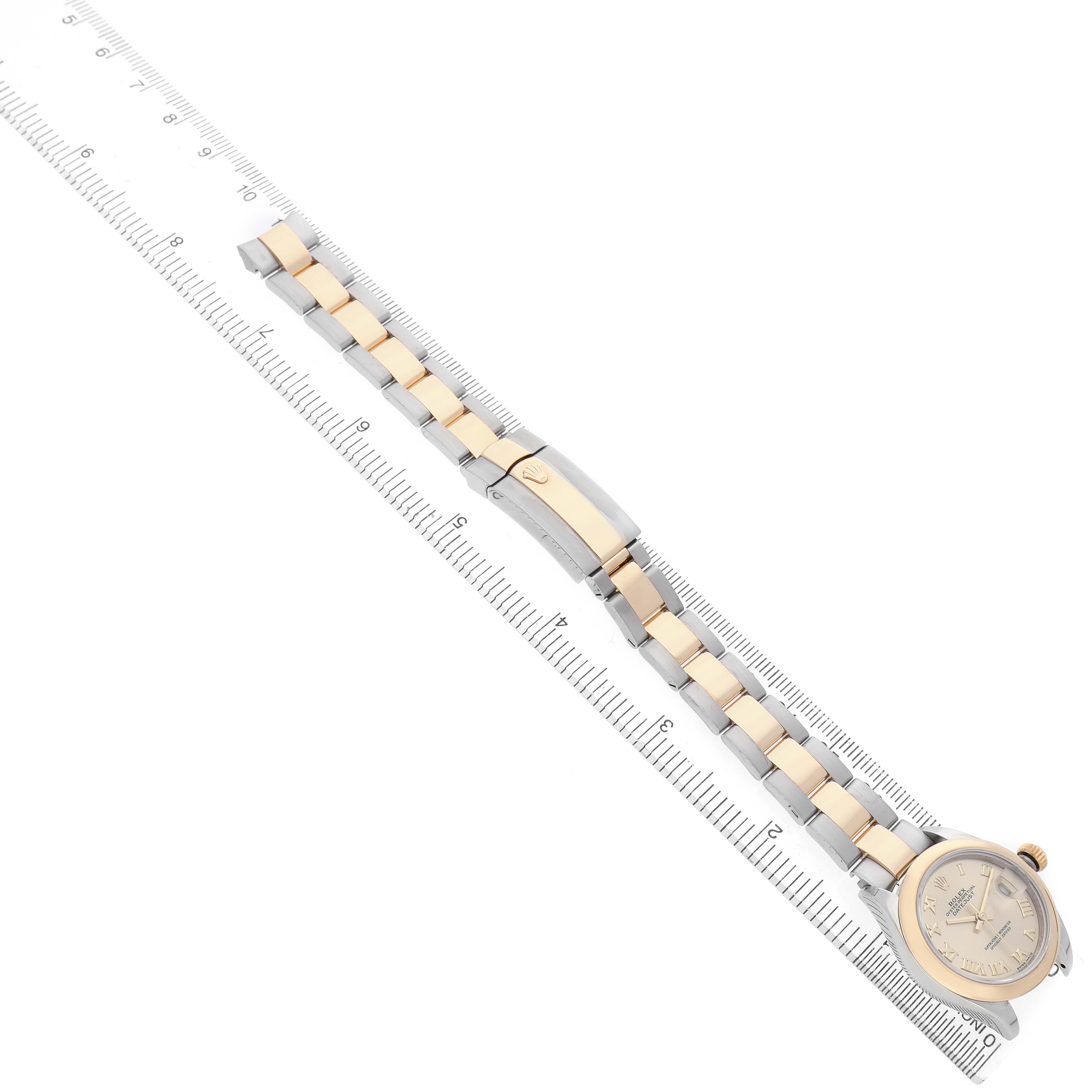 The image shows a Rolex Datejust 279163 Women's Steel and Gold (two tone) Champagne Dial watch positioned diagonally with its bracelet and clasp over a ruler.