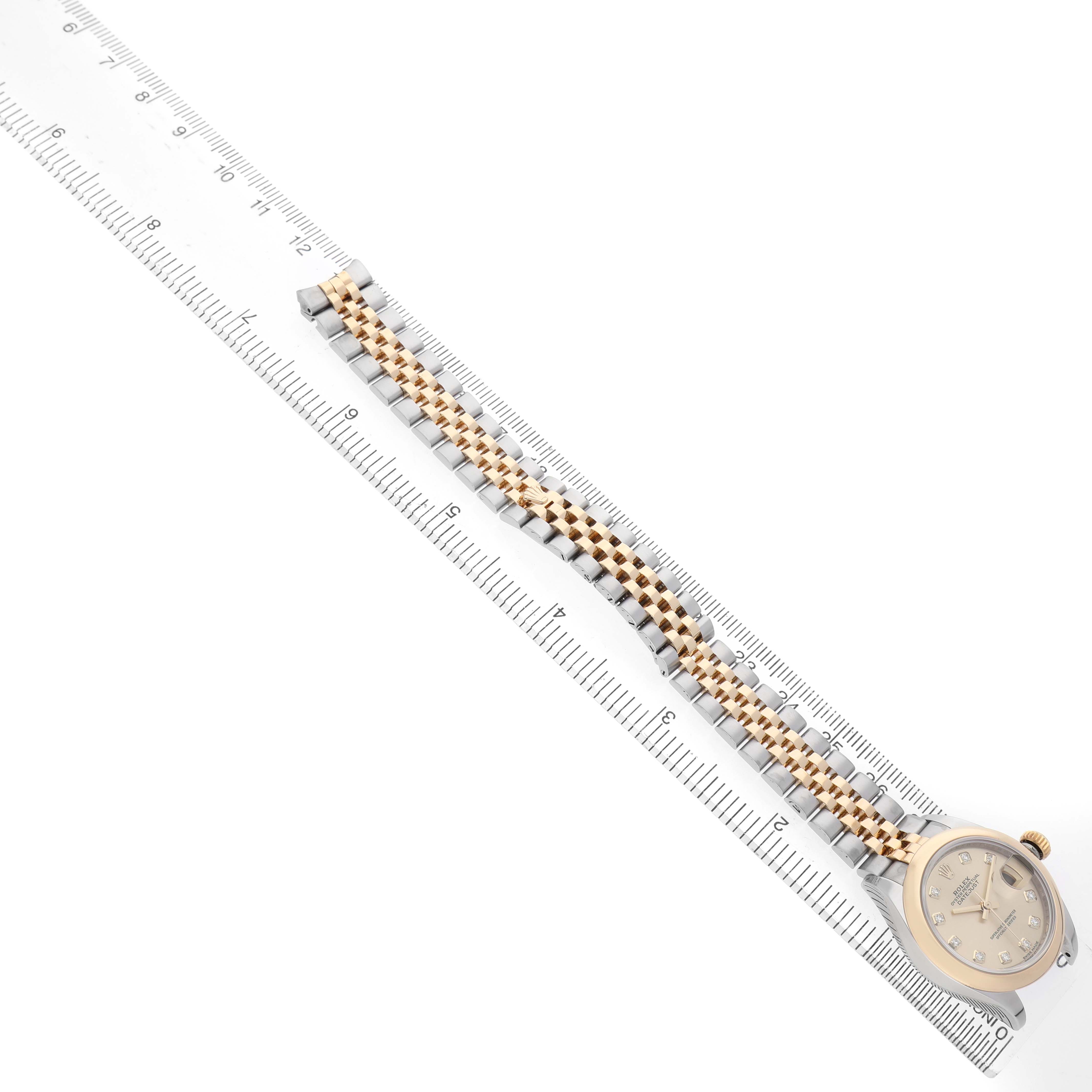 The Rolex Datejust 279163 Women's Steel and Gold (two tone) Champagne Dial watch is shown from a top-down angle, highlighting its bracelet and face alongside a measuring ruler.