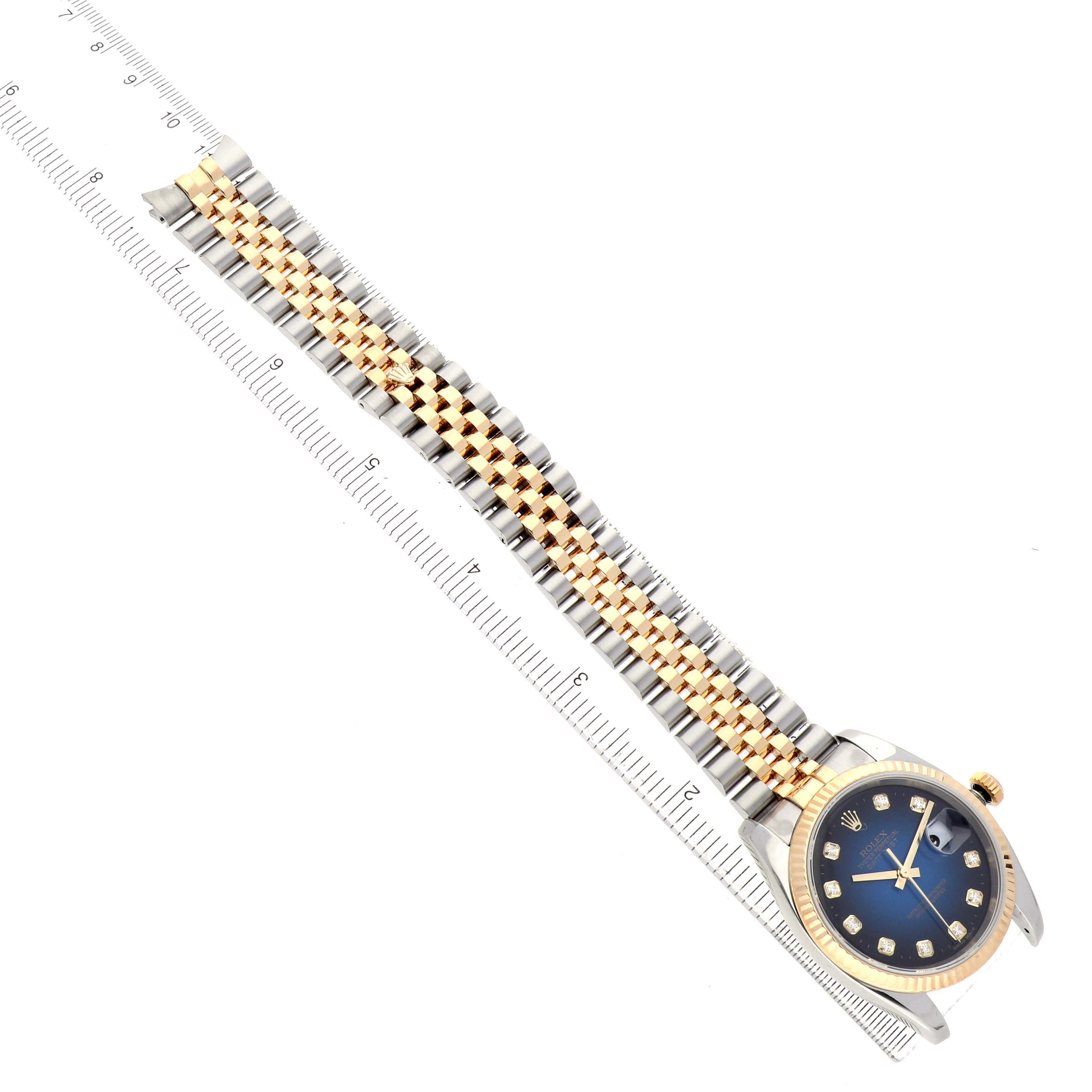 The Rolex Datejust 116233 Men's Steel and Gold (two tone) Blue Dial watch is shown from a top-down angle, displaying the dial, bezel, and two-tone bracelet with a ruler for scale.