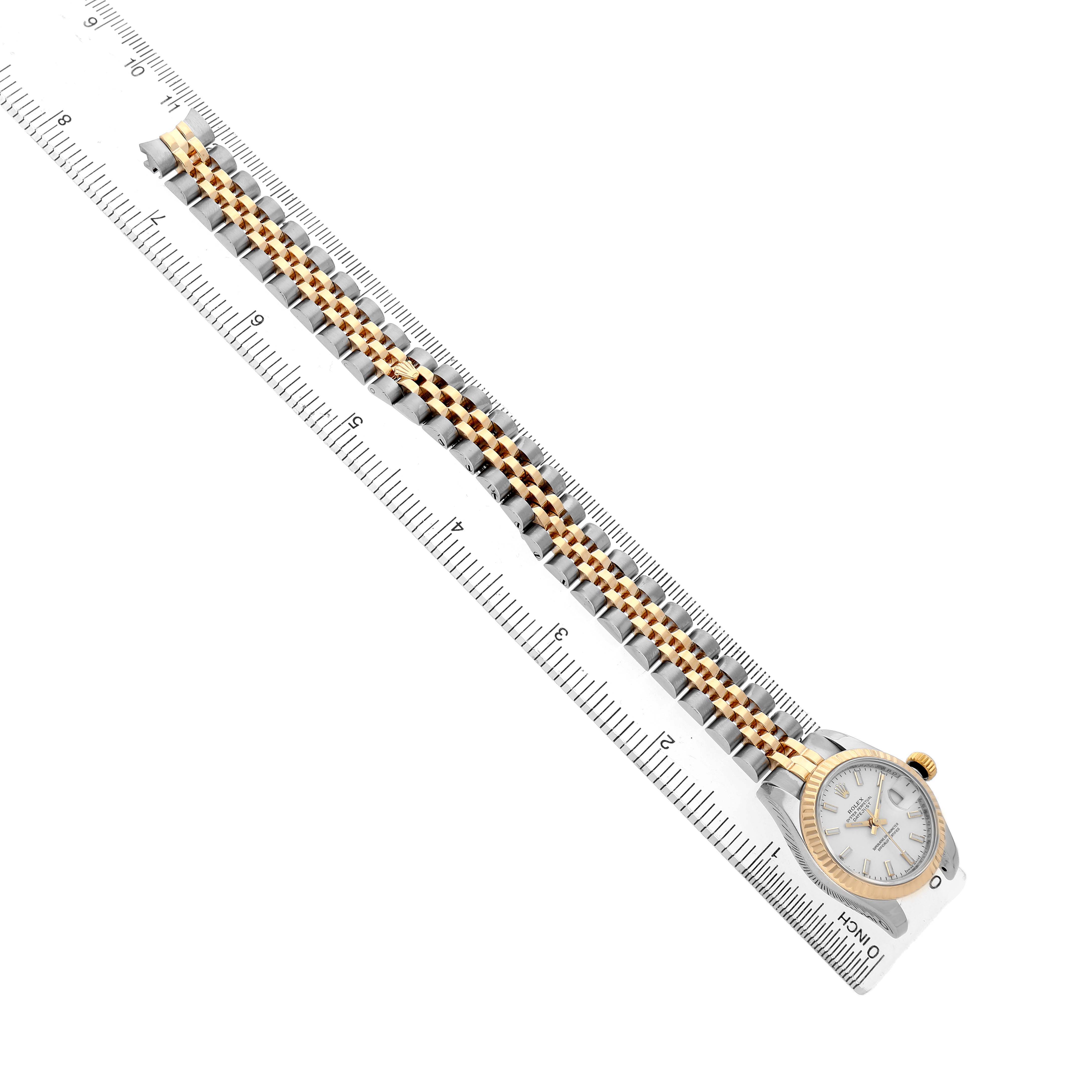The Rolex Datejust 179173 Women's Steel and Gold (two tone) White Dial watch is shown from an overhead angle alongside a ruler, highlighting the bracelet and dial.