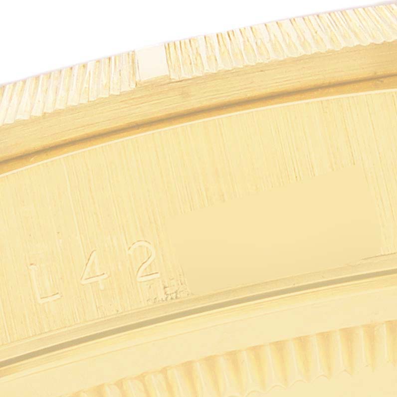 This close-up image shows a portion of the bezel and engraved serial number of a Rolex President 18248 Men's Yellow Gold Champagne Dial 18248 Men's Yellow Gold Champagne Dial model watch.