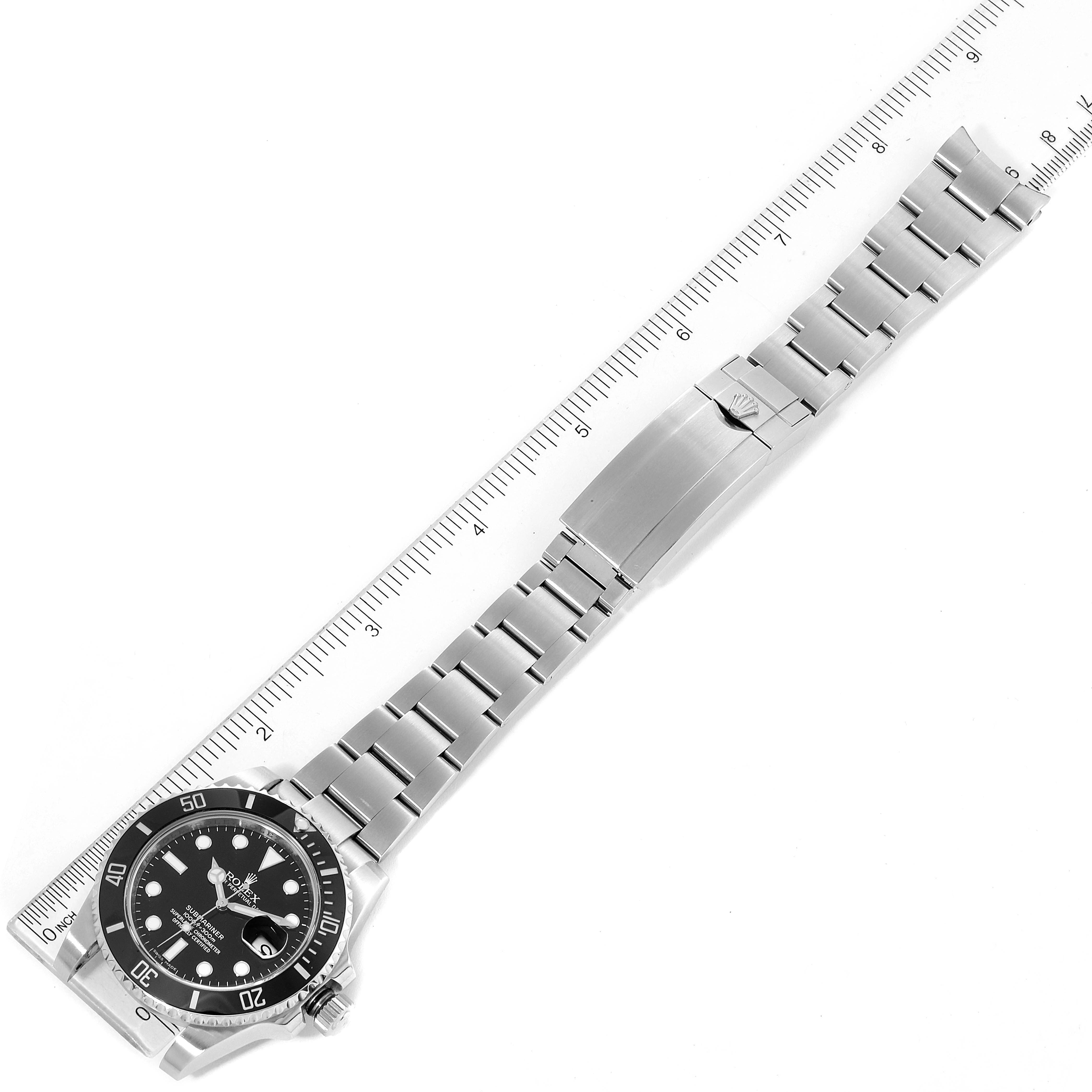 This image shows a Rolex Submariner 116610LN Men
s Stainless Steel Black Dial 116610LN Men
s Stainless Steel Black Dial watch laid flat with its bracelet fully extended alongside a ruler.