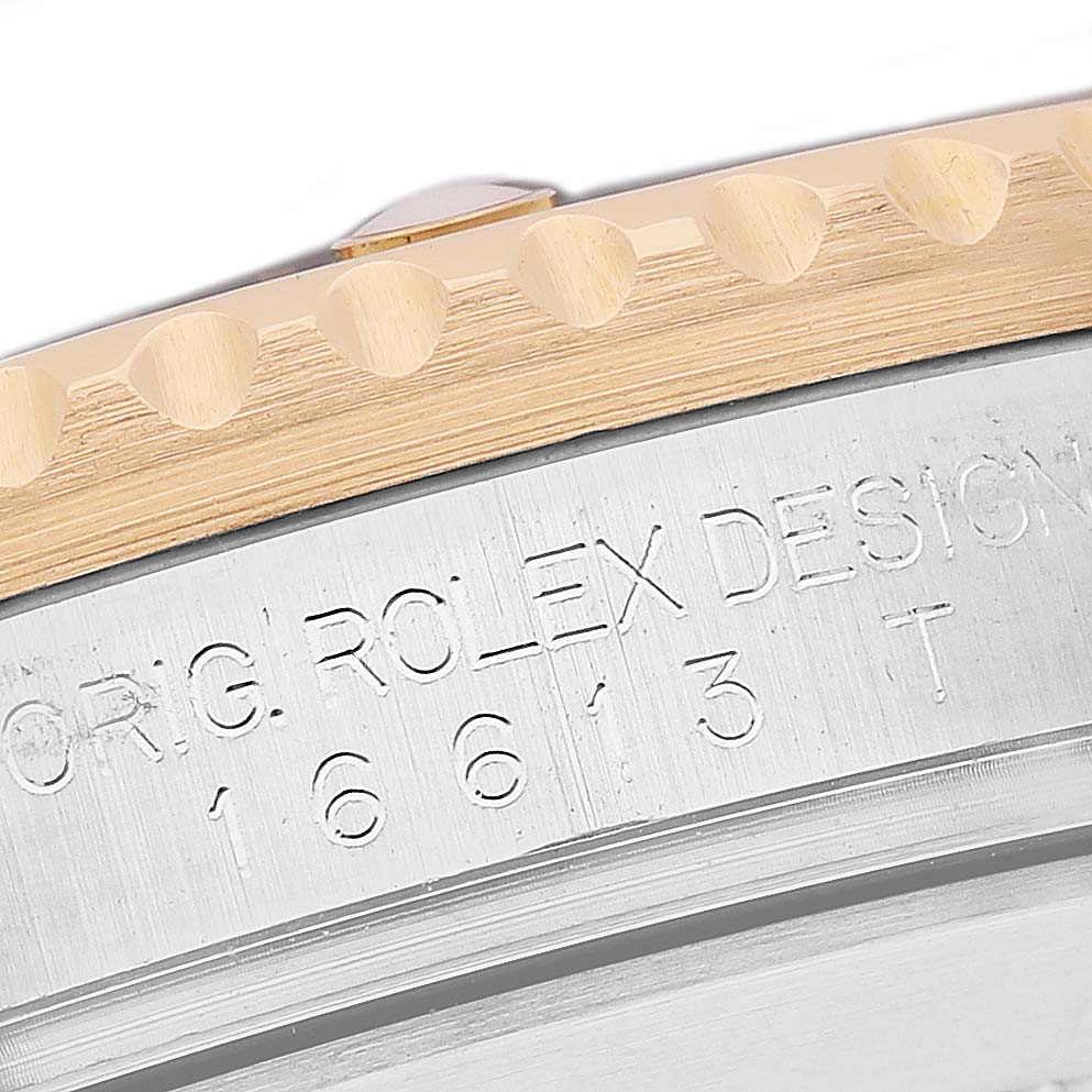 The image shows a close-up of the Rolex Submariner 16613 Men's Steel and Gold (two tone) Black Dial's serial engraving and side of the bezel from an angle highlighting the textured edge.