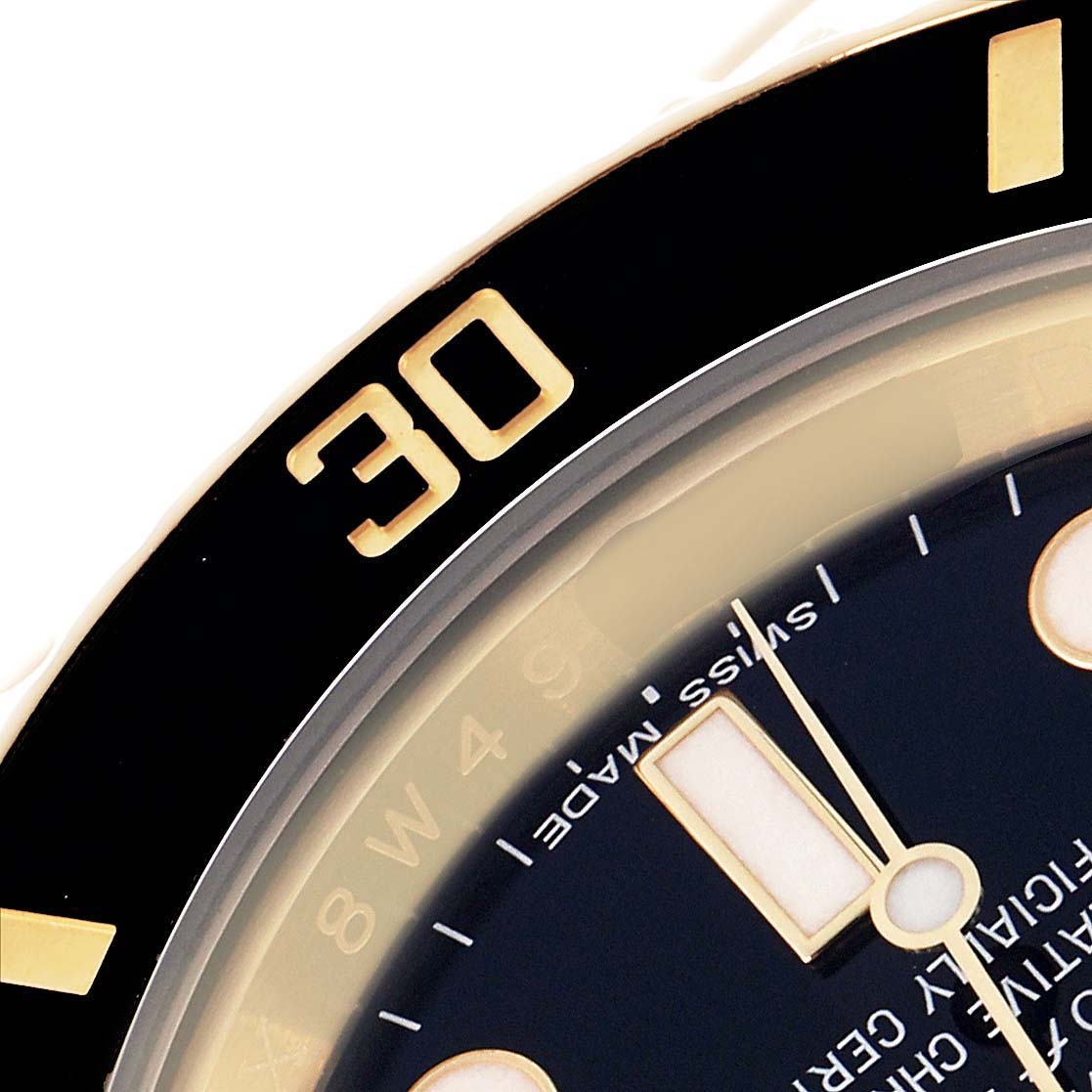 The image shows a close-up of the bezel and part of the dial of a Rolex Submariner 116618 Men's Yellow Gold Black Dial watch.