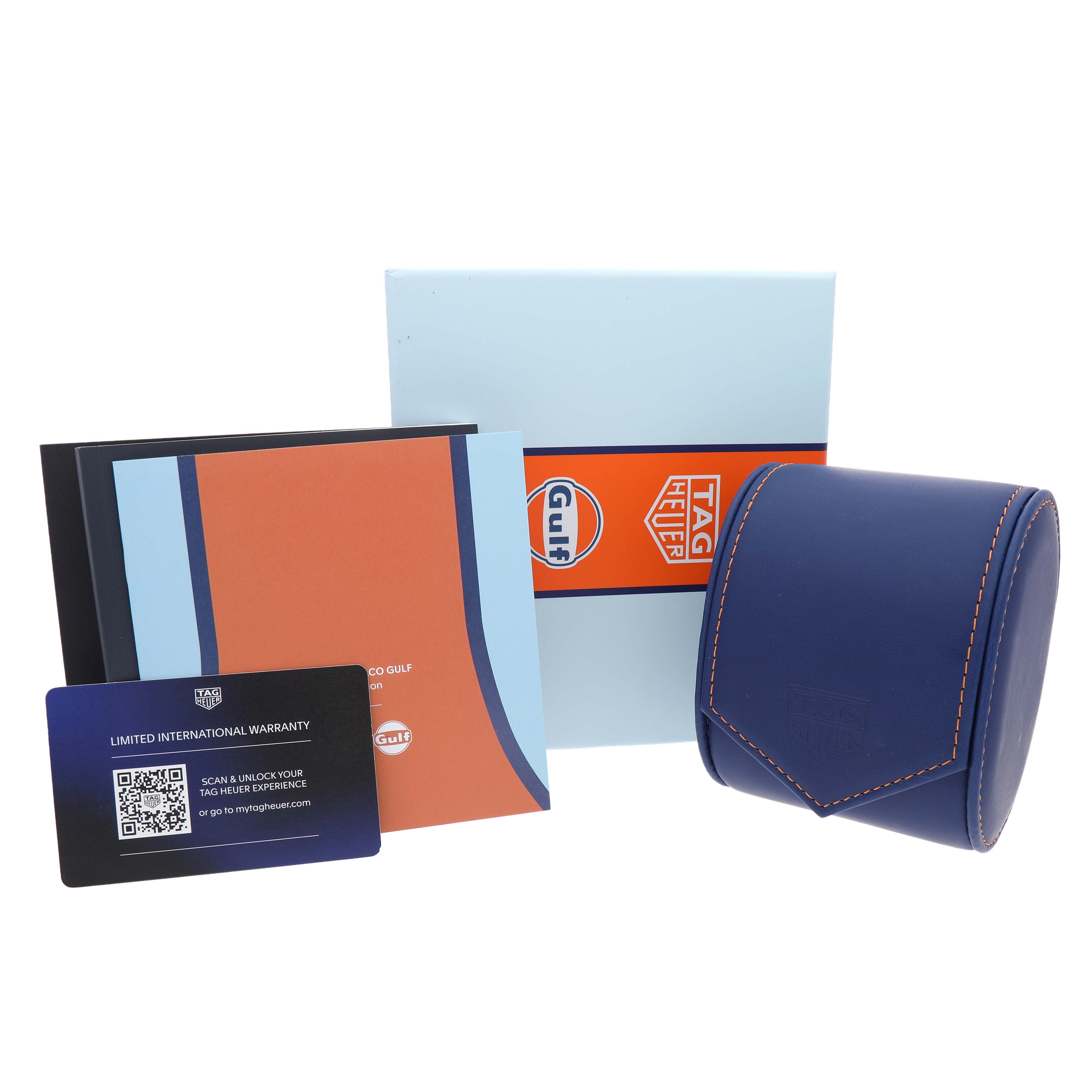 The image shows the packaging and accessories for a Tag Heuer Monaco CBL2115 Men's Stainless Steel Blue Dial watch, including a case, box, manuals, and warranty card.