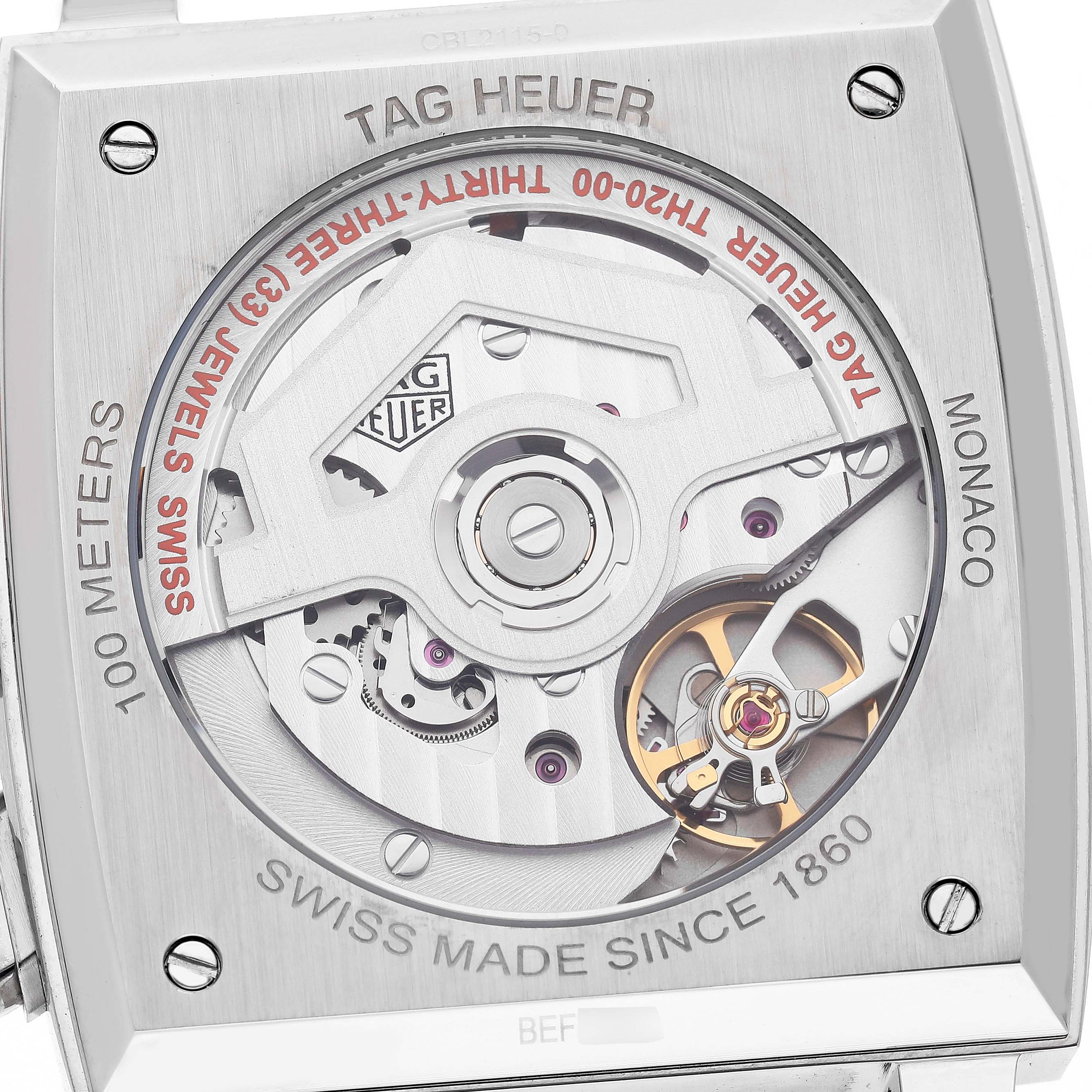 The image shows the back of a Tag Heuer Monaco CBL2115 Men's Stainless Steel Blue Dial watch, highlighting its exposed movement and intricate mechanical parts.