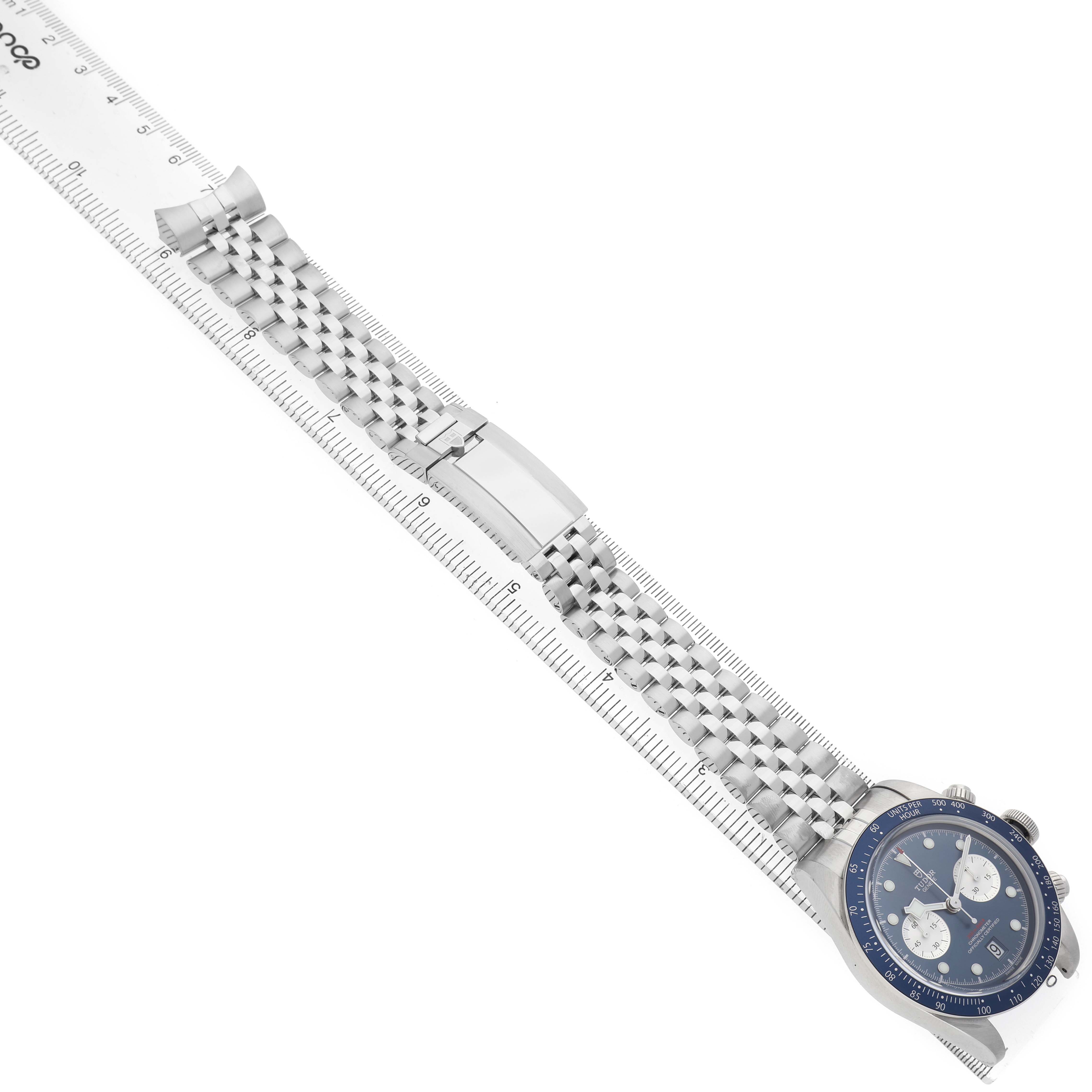 The Tudor Heritage Black Bay M79360B-0002 Men's Stainless Steel Blue Dial watch is shown from a top angle, displaying the full face, bracelet, and clasp next to a ruler.