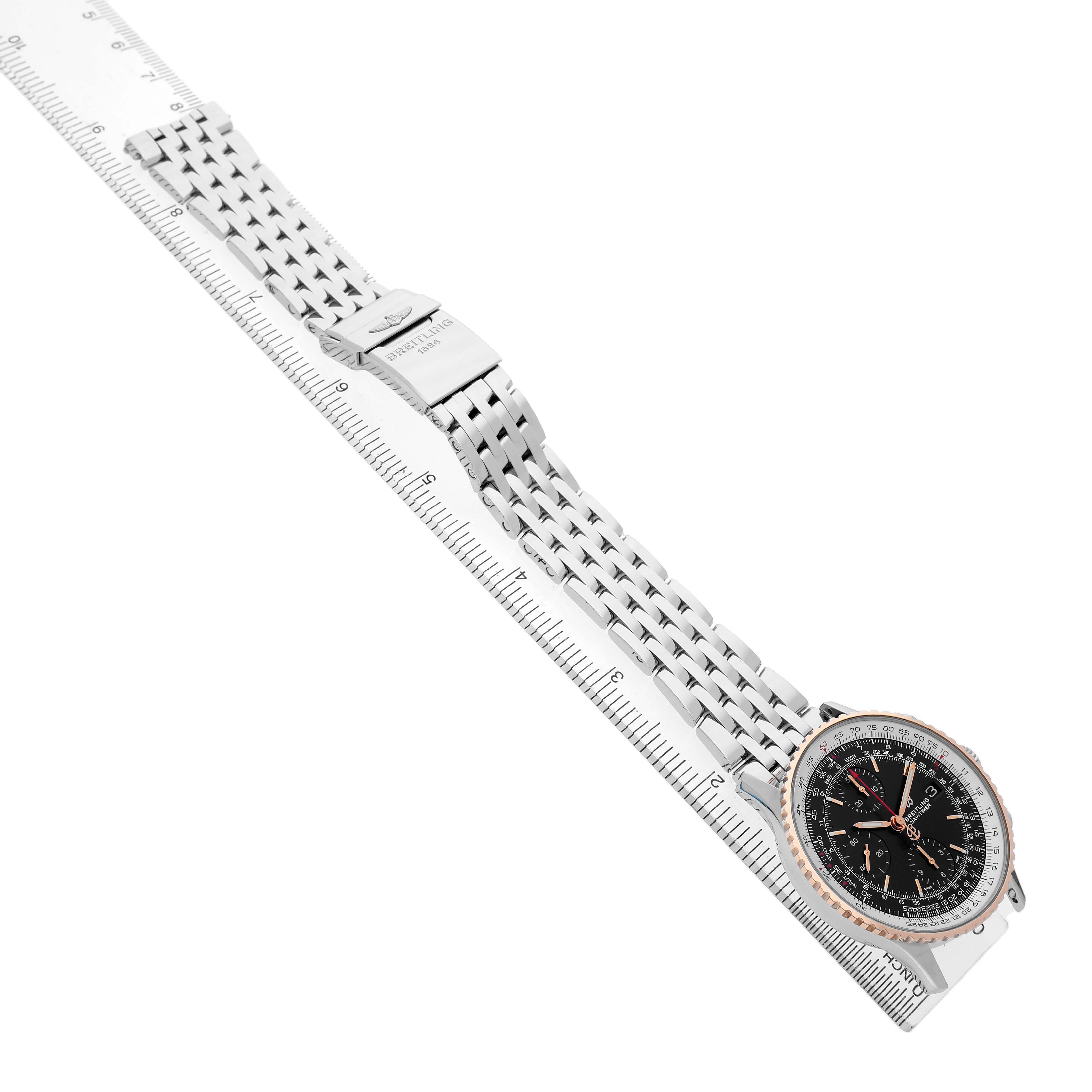 The image shows a Breitling Navitimer U13324211B1X1 Men's Steel and Gold (two tone) Black Dial watch at an angle, displaying the full bracelet and clasp, laid alongside a ruler.