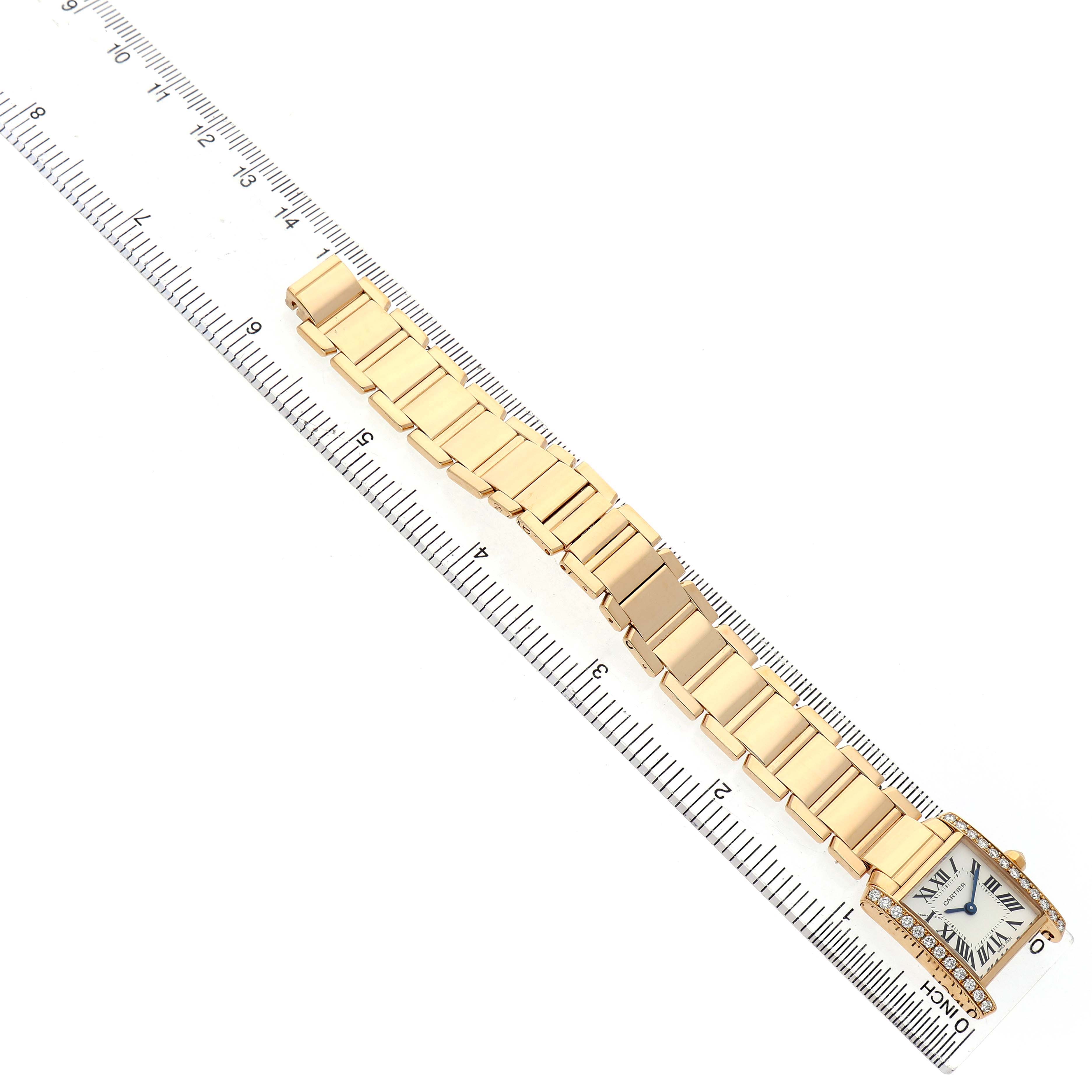 The Cartier Tank Française watch is displayed flat on its band alongside a ruler, highlighting its gold bracelet and square face.