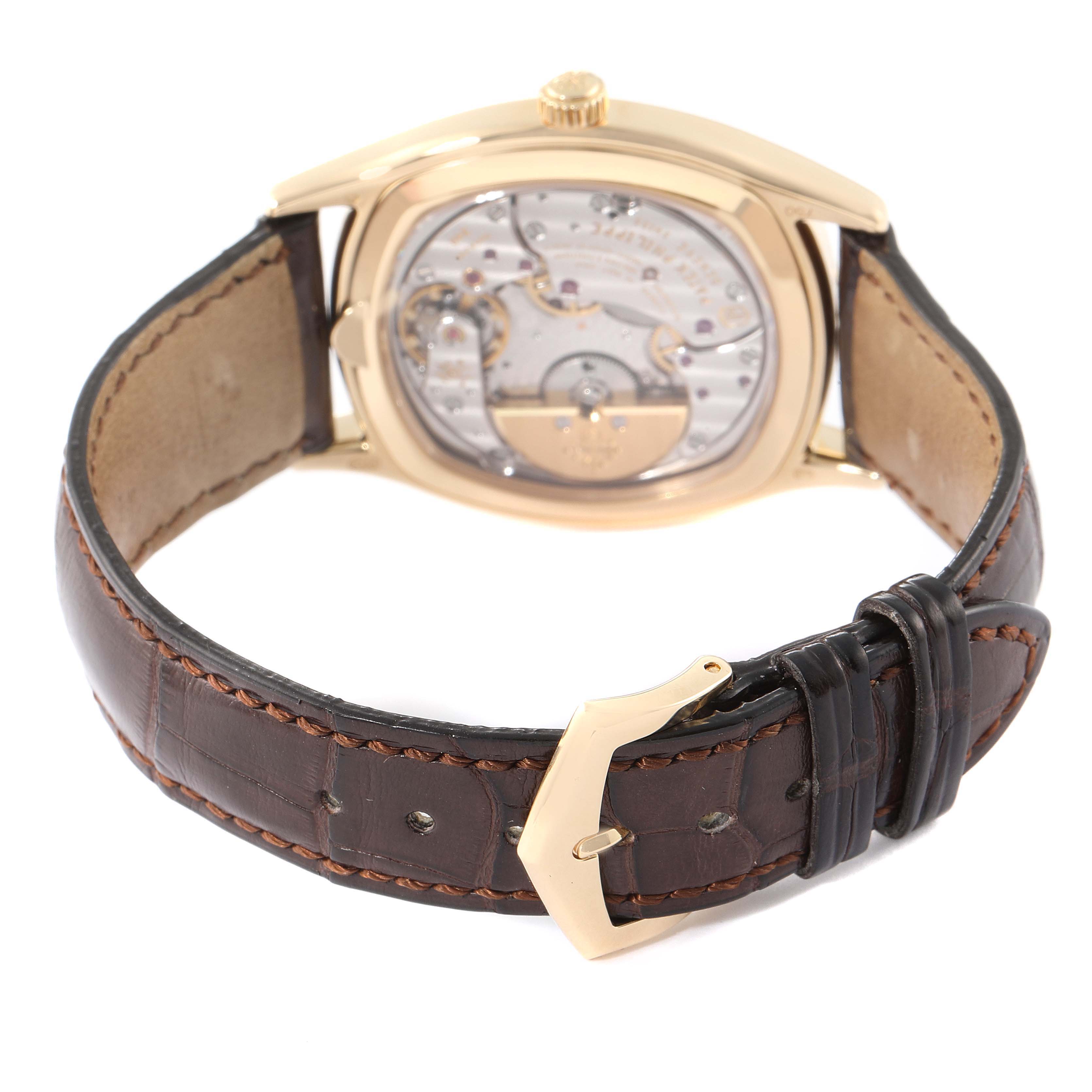 The image shows the back view of a Patek Philippe Complications 5940J - 001 Men's Yellow Gold Silver Dial 5940J - 001 Men's Yellow Gold Silver Dial watch, focusing on its movement and leather strap with a buckle.