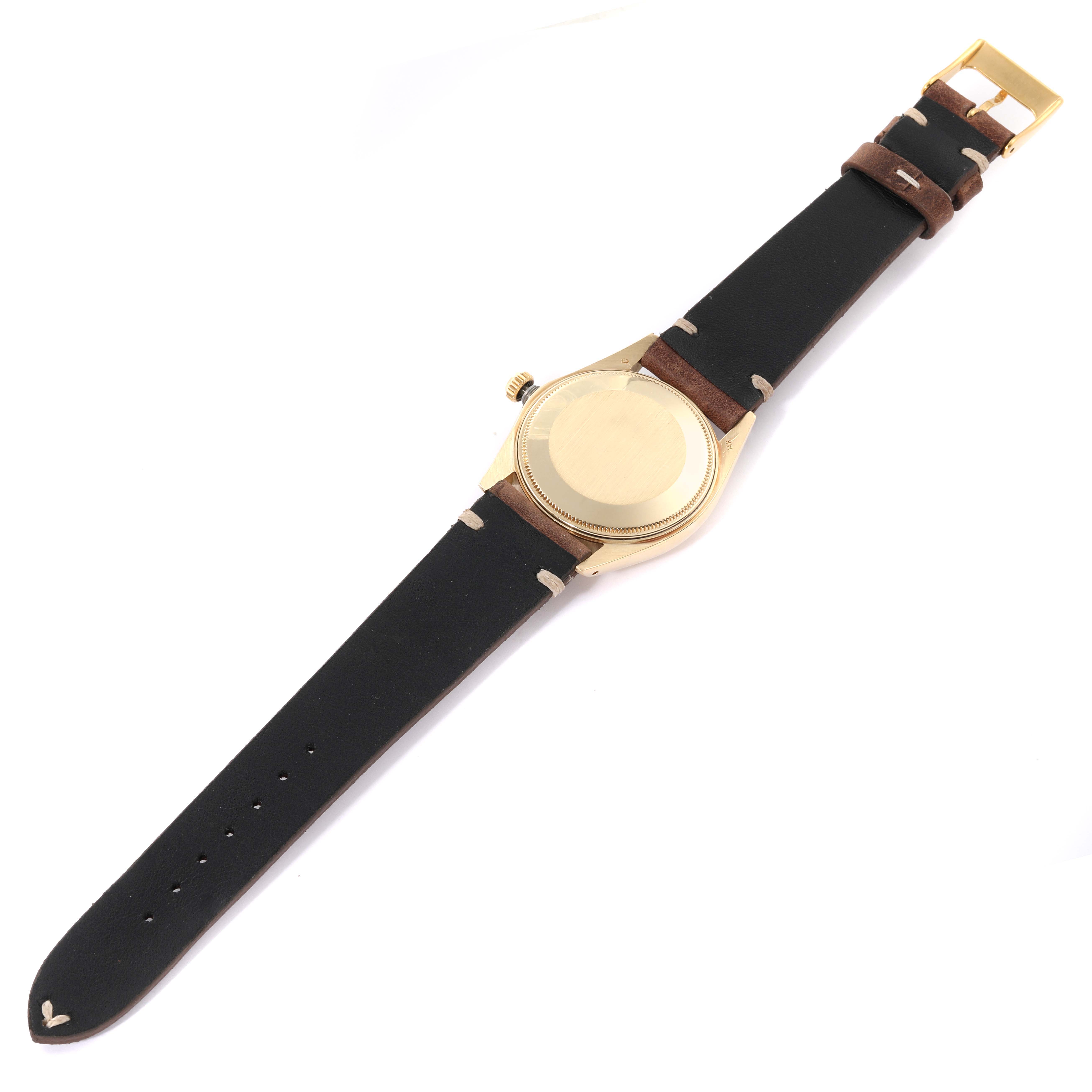 The image shows the back view of a Vintage Collection Rolex watch with a black leather strap and gold casing.