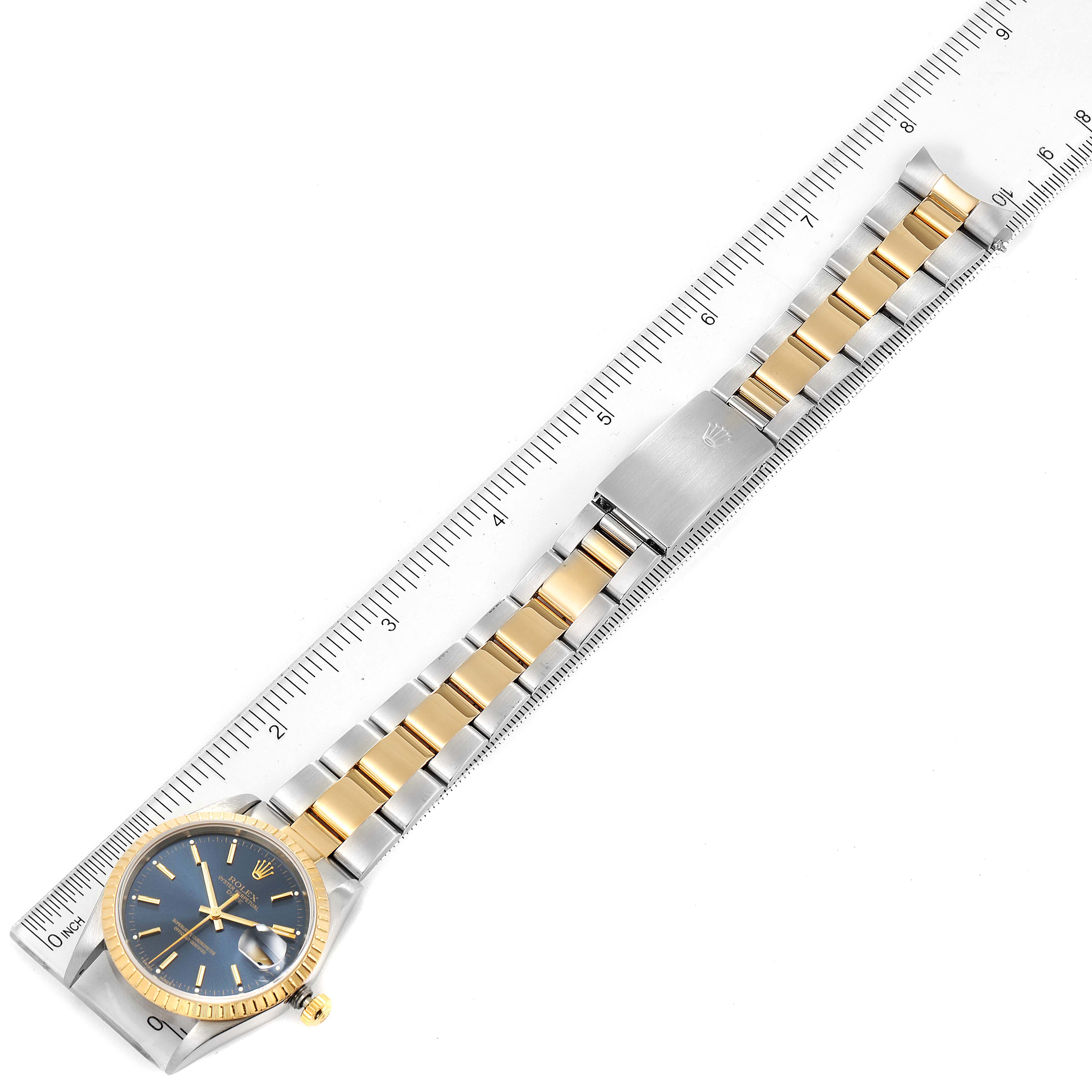 The image shows a top-down view of a Rolex Datejust 15223 Men's Steel and Gold (two tone) Blue Dial 15223 Men's Steel and Gold (two tone) Blue Dial watch, highlighting the dial, bezel, bracelet, and clasp adjacent to a ruler.