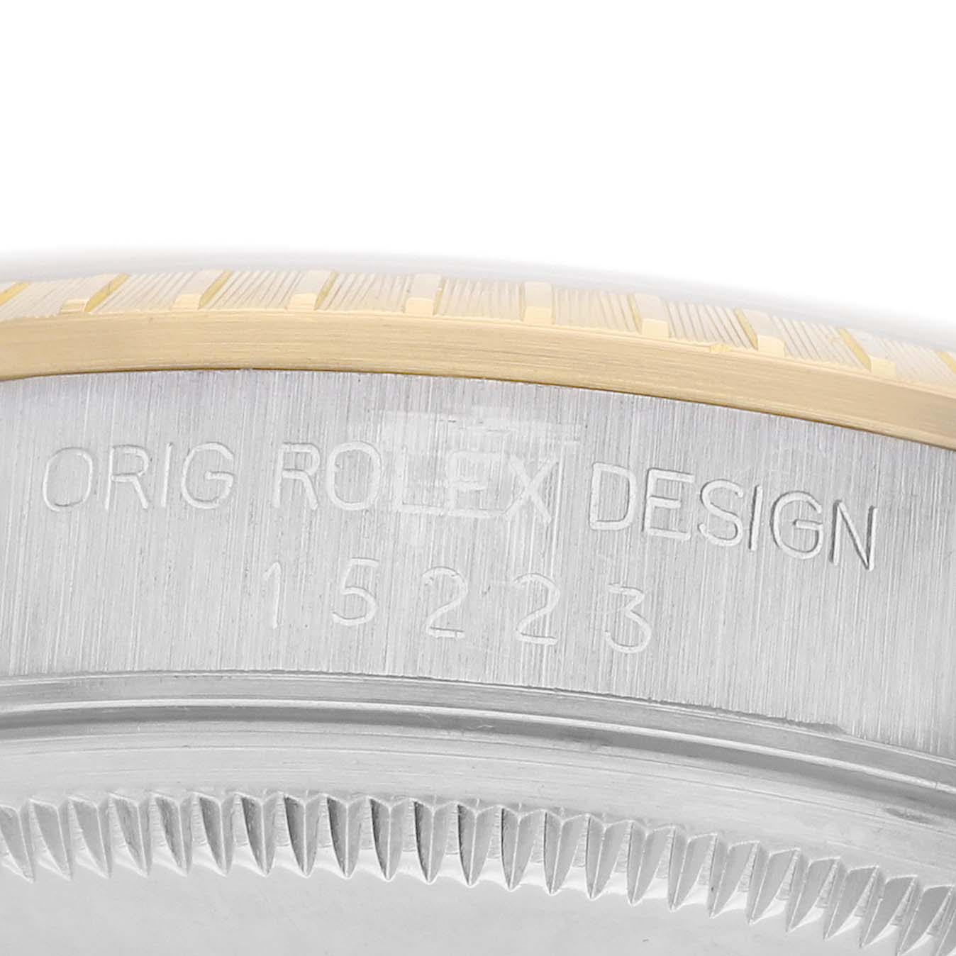 The image shows the side view of a Rolex Date 15223 Men's Steel and Gold (two tone) Champagne Dial model, highlighting the case with engraved model number and design details.