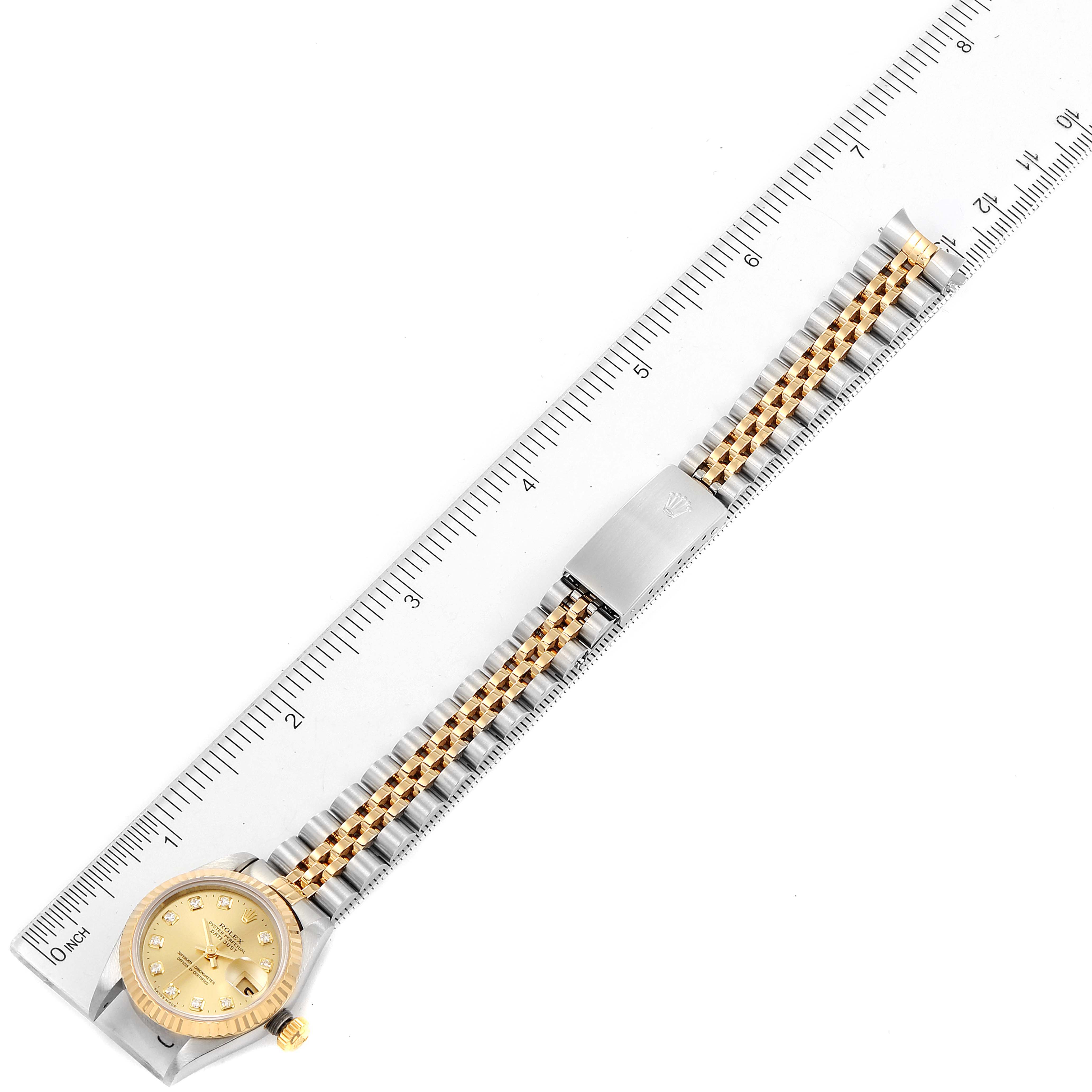 This is an overhead view of a Rolex Datejust 69173 Women's Steel and Gold (two tone) Champagne Dial 69173 Women's Steel and Gold (two tone) Champagne Dial watch laid alongside a ruler, showing the full bracelet and face.