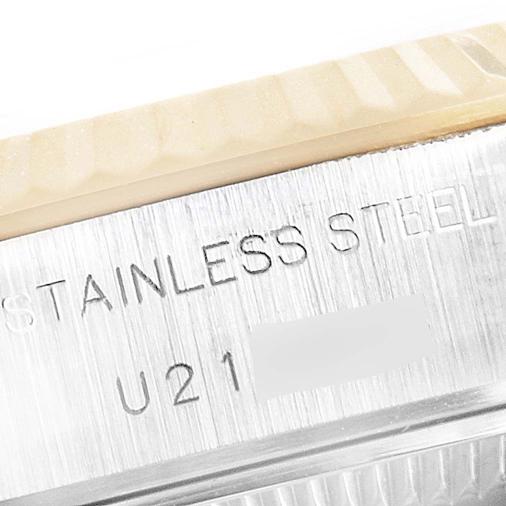 This image shows a close-up of the stainless steel case of a Rolex Datejust 69173 Women's Steel and Gold (two tone) Champagne Dial 69173 Women's Steel and Gold (two tone) Champagne Dial watch, including part of the bezel and engraved text.