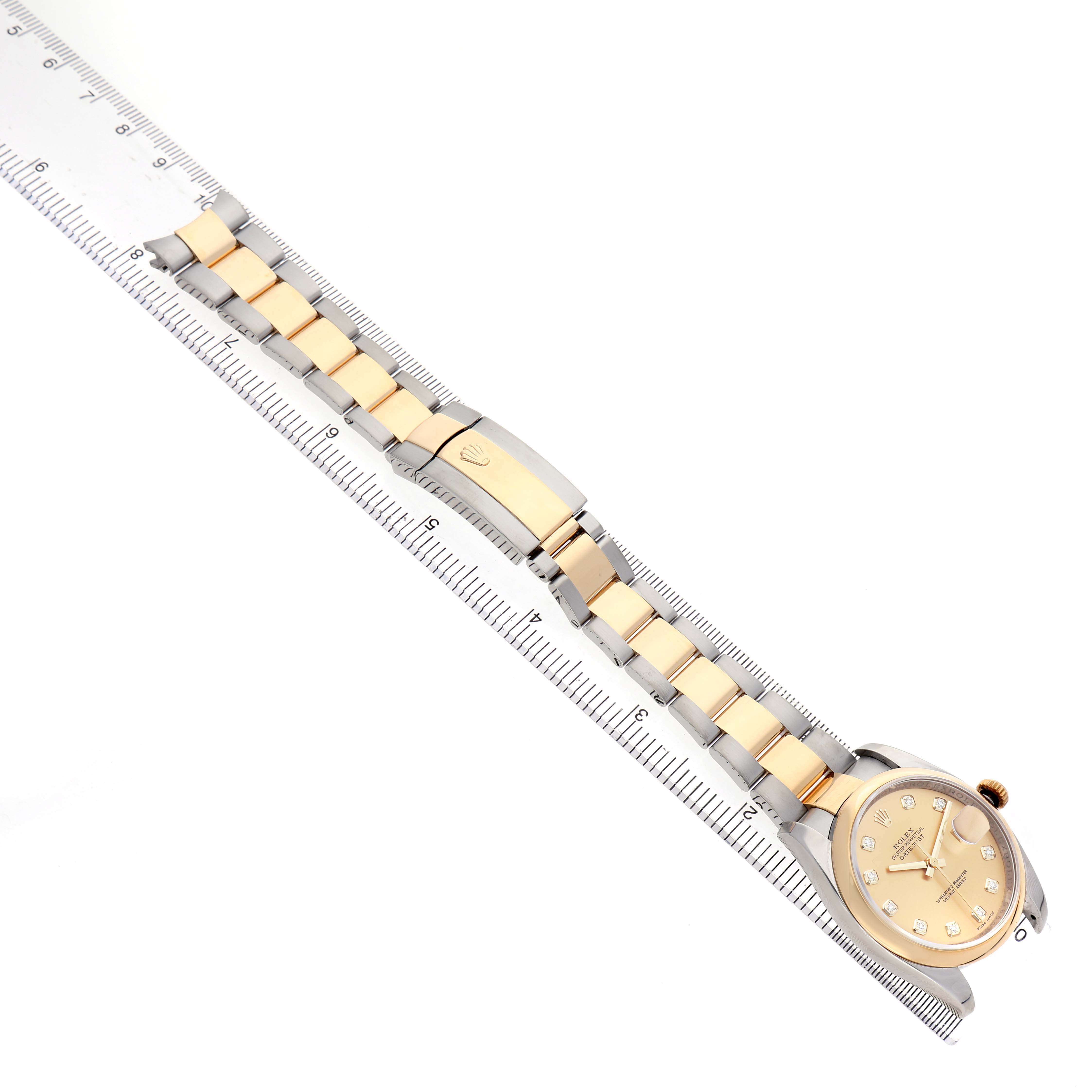 The Rolex Datejust 116203 Men's Steel and Gold (two tone) Champagne Dial watch is shown diagonally with the bracelet and clasp visible alongside a ruler for scale.