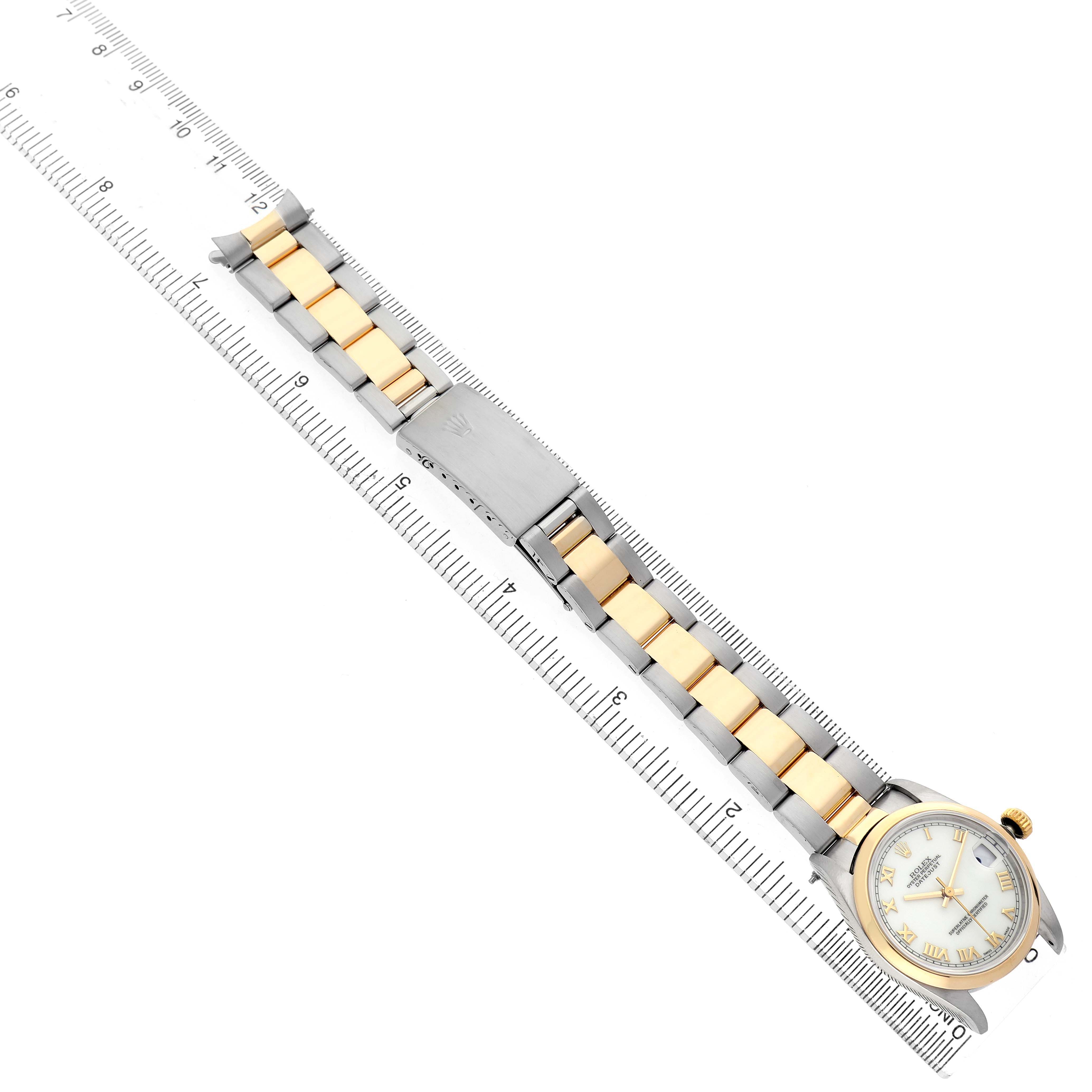 The Rolex Datejust 68243 Women's Steel and Gold (two tone) White Dial watch is shown from a top view, highlighting the face and the two-tone bracelet alongside a ruler for scale.