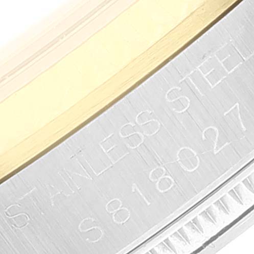 This close-up image of the Rolex Datejust 68273 Women's Steel and Gold (two tone) Black Dial 68273 Women's Steel and Gold (two tone) Black Dial watch shows a portion of the stainless steel case with engraved text.