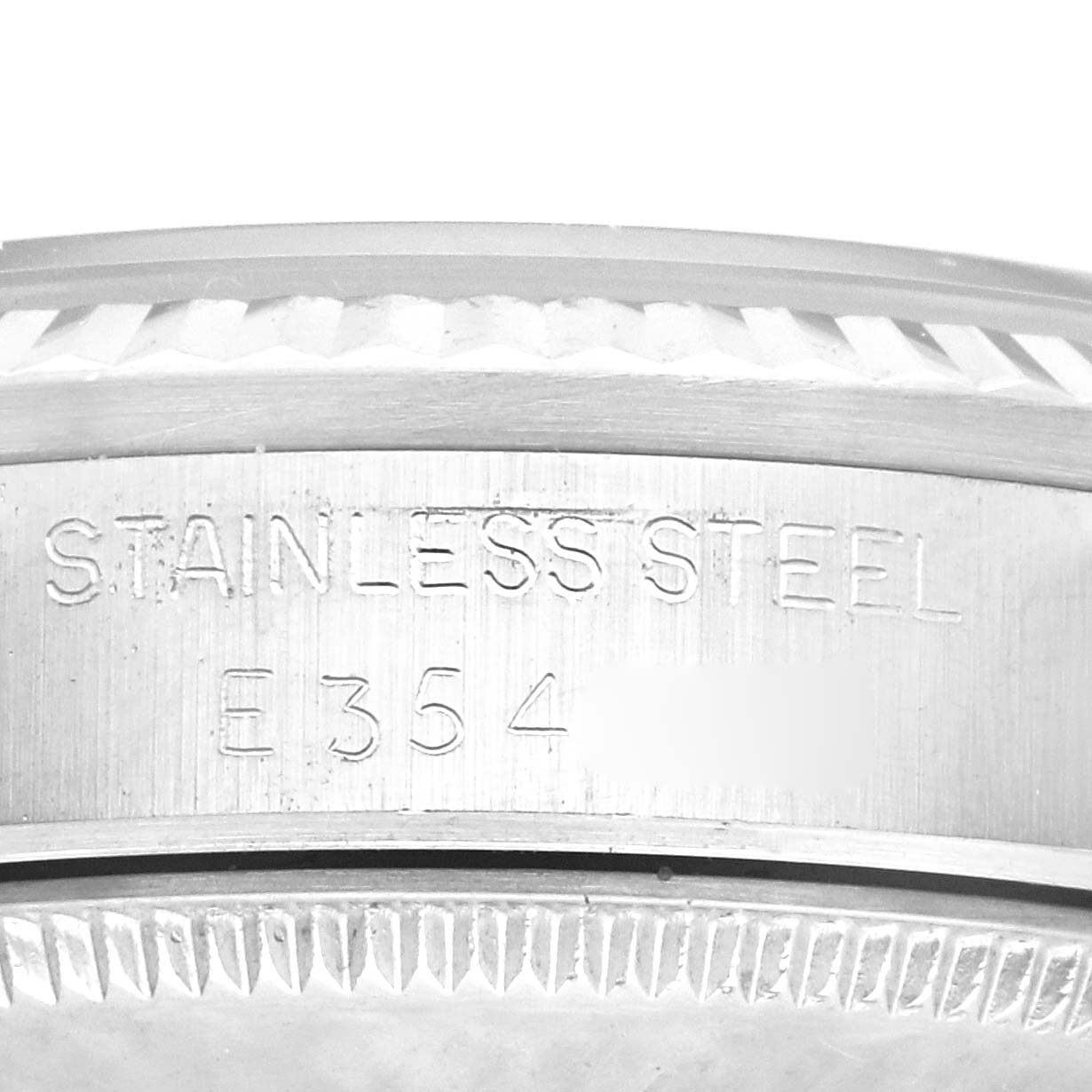 The image shows a close-up of the edge of a stainless steel mid-size Rolex watch case, including part of the bezel and serial number.