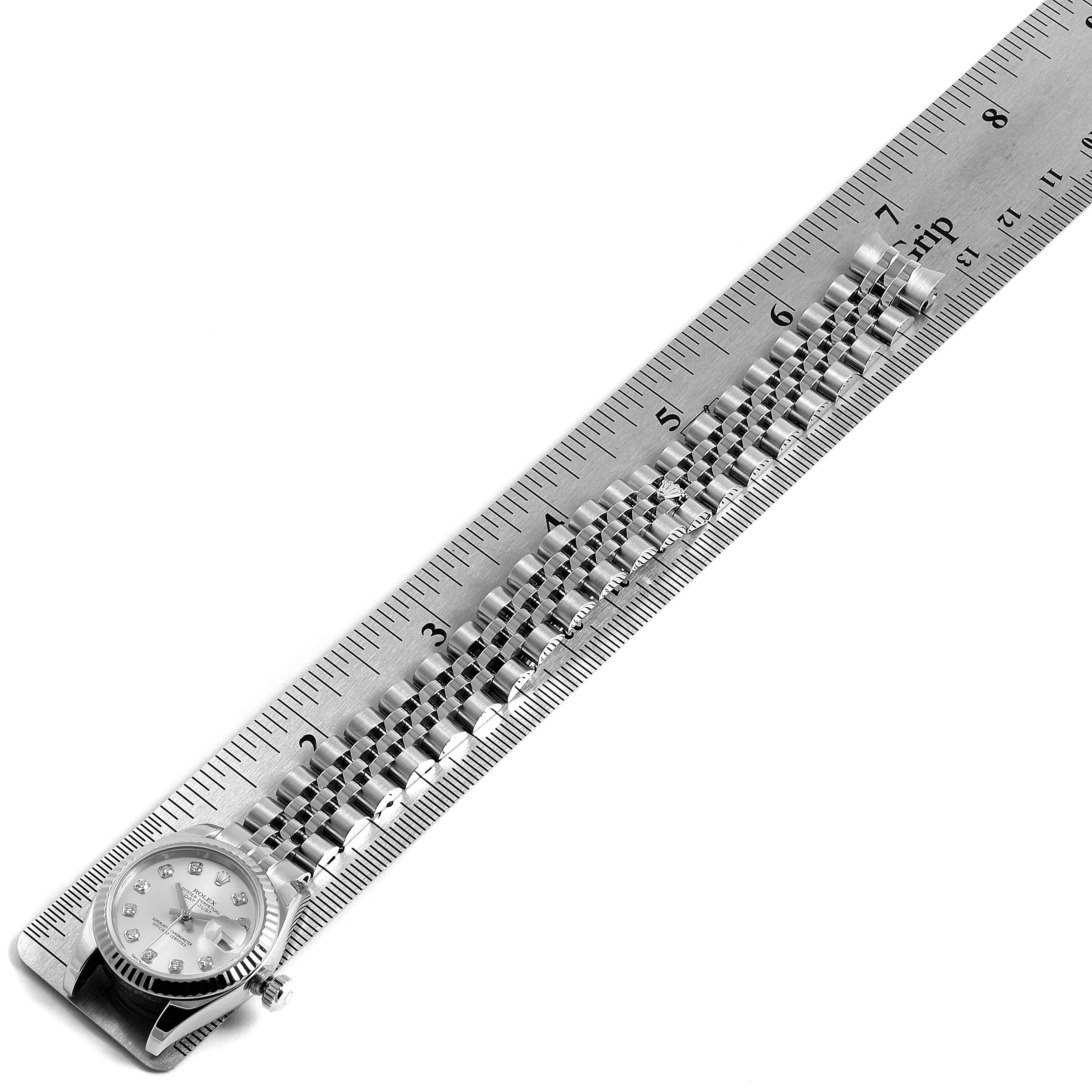 The image shows the face and band of a Rolex Datejust 179174 Women
s Stainless Steel White Dial 179174 Women
s Stainless Steel White Dial watch aligned with a metal ruler.