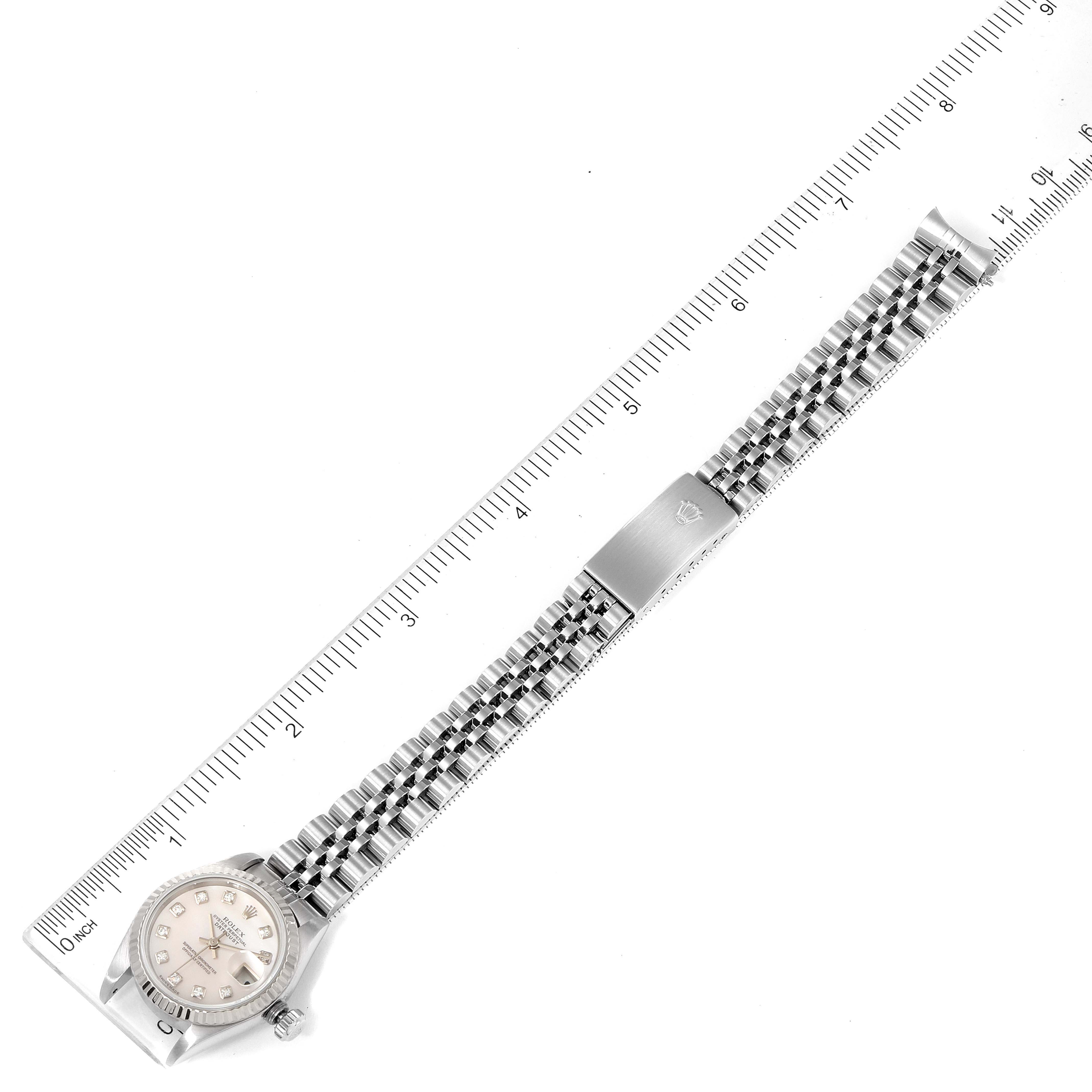 The Rolex Datejust 79174 Women's Stainless Steel Mother of Pearl Dial 79174 Women's Stainless Steel Mother of Pearl Dial watch is shown laying flat with its entire face, bracelet, and clasp visible against a ruler backdrop.