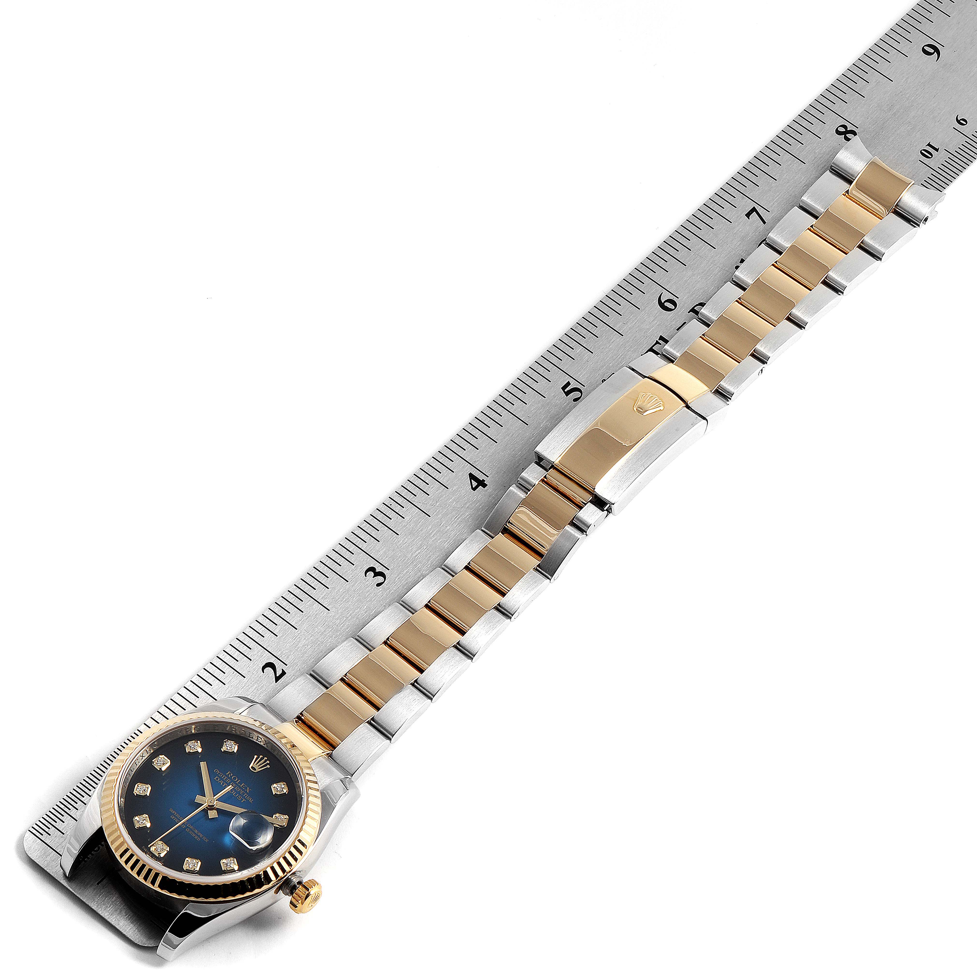 The image shows a top view of a Rolex Datejust 116233 Men's Steel and Gold (two tone) Blue Dial 116233 Men's Steel and Gold (two tone) Blue Dial watch with its strap aligned along a ruler.