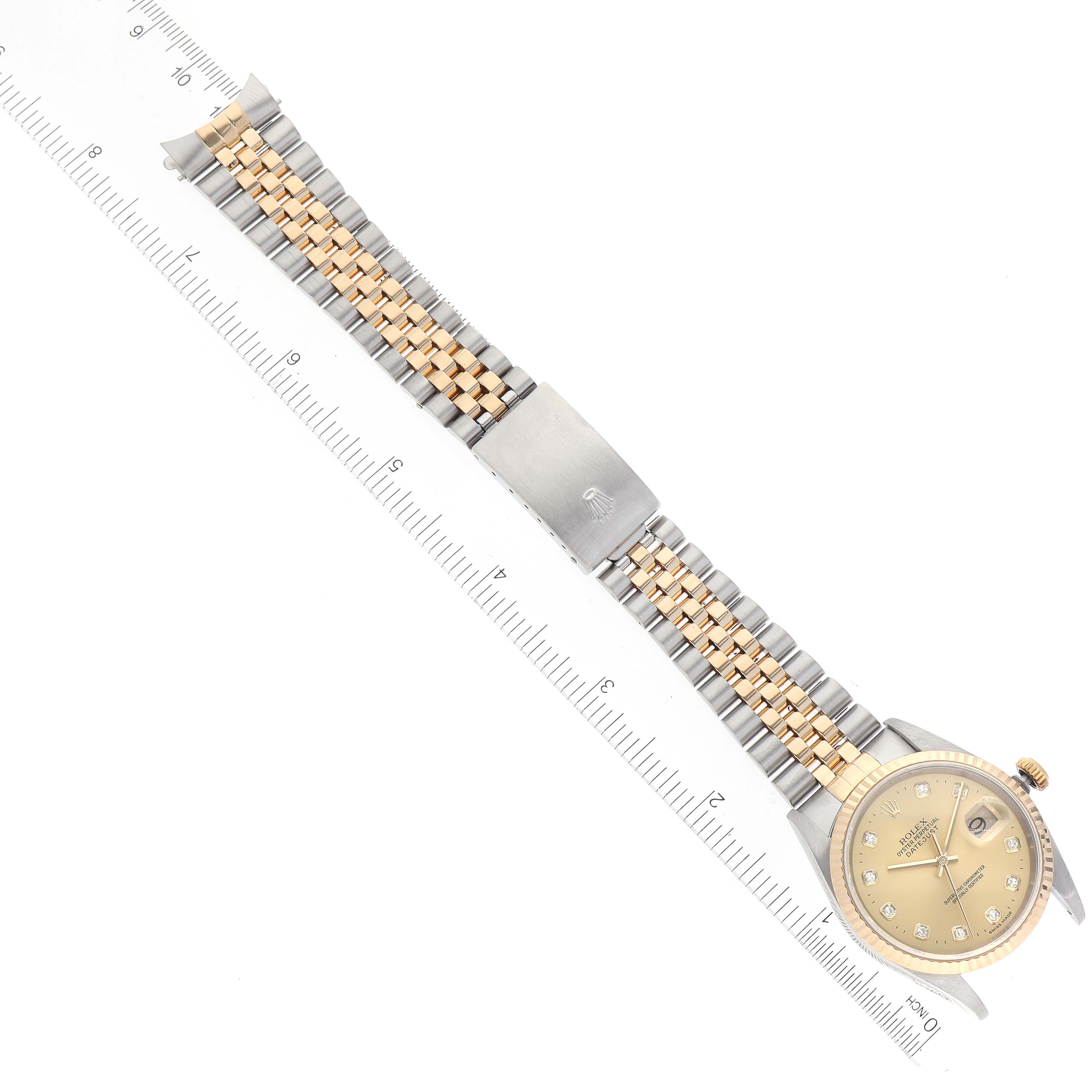 The image displays a Rolex Datejust 16233 Men's Steel and Gold (two tone) Champagne Dial 16233 Men's Steel and Gold (two tone) Champagne Dial watch laid flat, showing the dial, bezel, and two-tone bracelet against a ruler for scale.