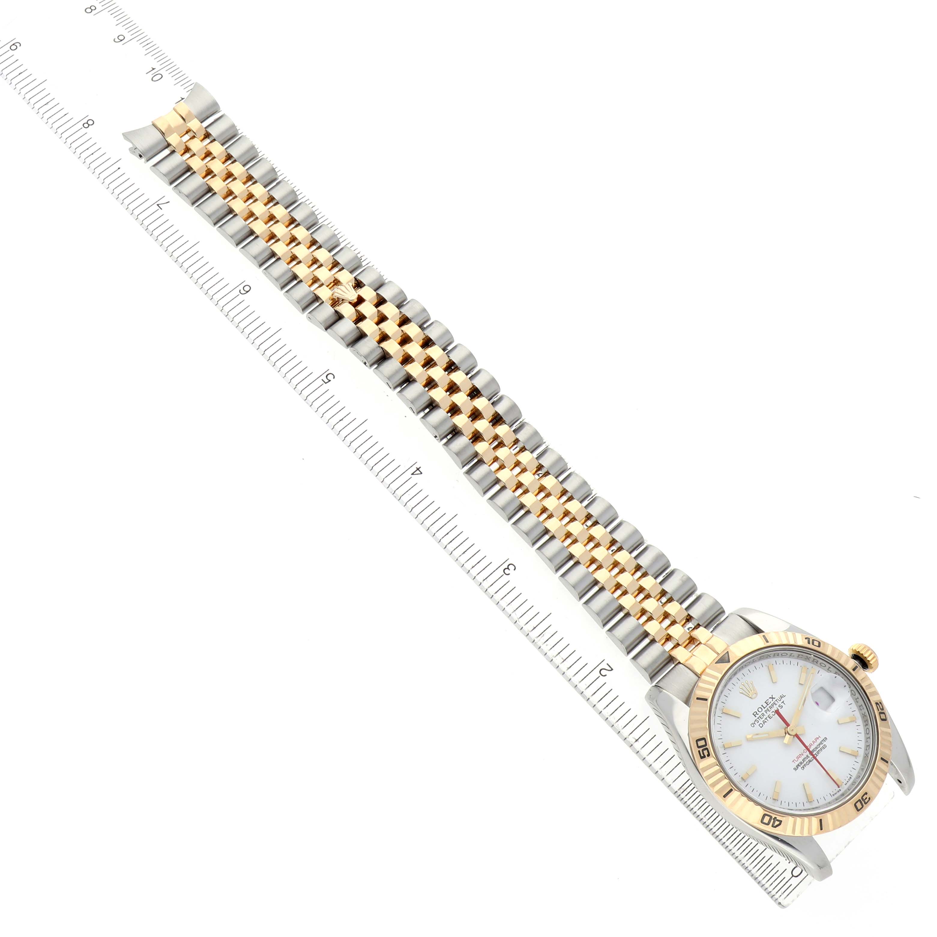 The Rolex Datejust 116263 Men's Steel and Gold (two tone) White Dial watch is shown from an overhead angle, displaying the face, bezel, and full bracelet alongside a ruler.