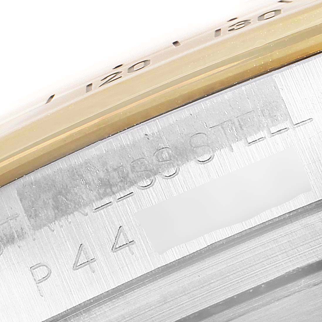 This close-up image shows the engraved text on the side of the bezel and case of a Rolex Daytona 116523 Men's Steel and Gold (two tone) White Dial 116523 Men's Steel and Gold (two tone) White Dial watch.