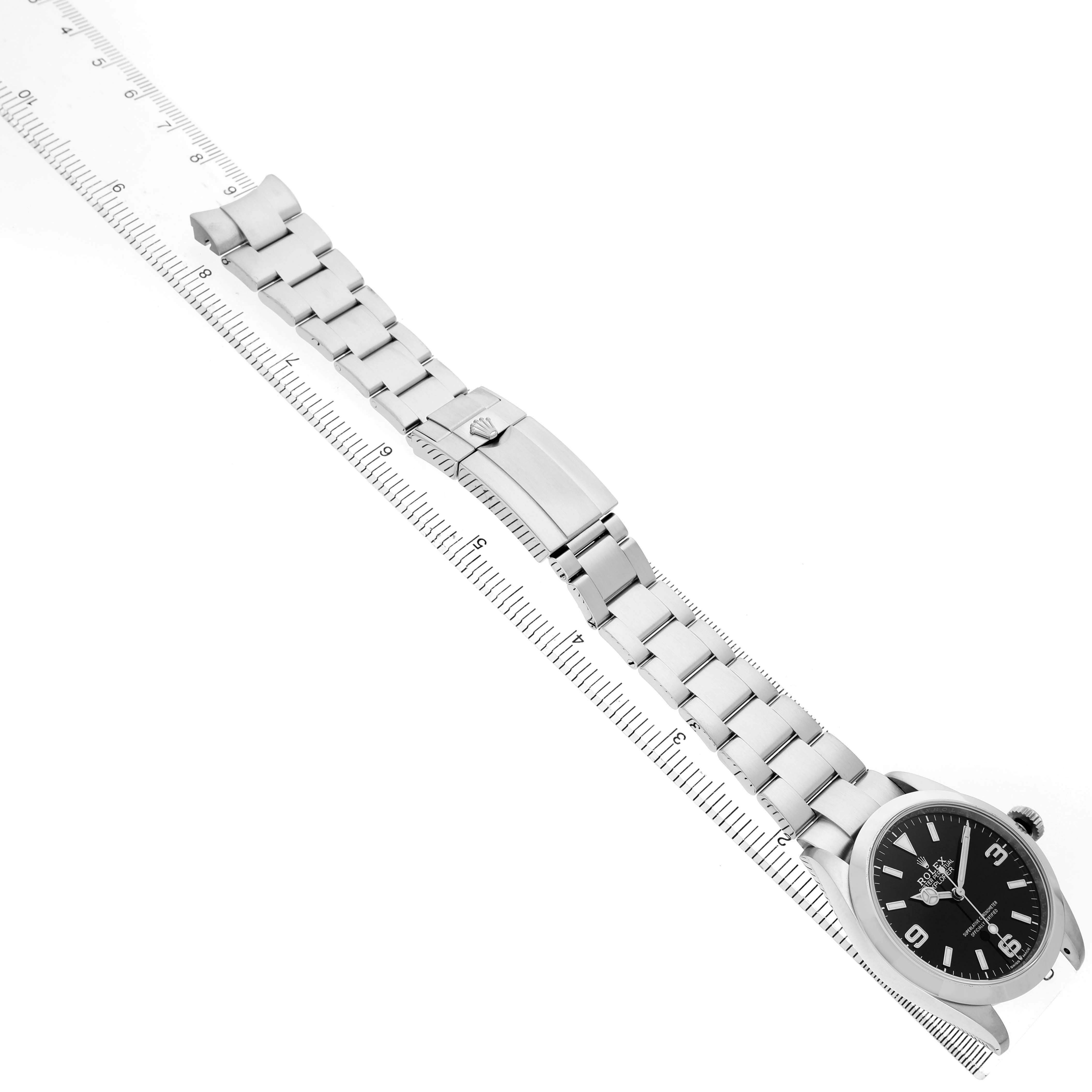 The Rolex Explorer 224270 Men's Stainless Steel Black Dial watch is positioned diagonally with the bracelet extended and visible alongside a ruler.