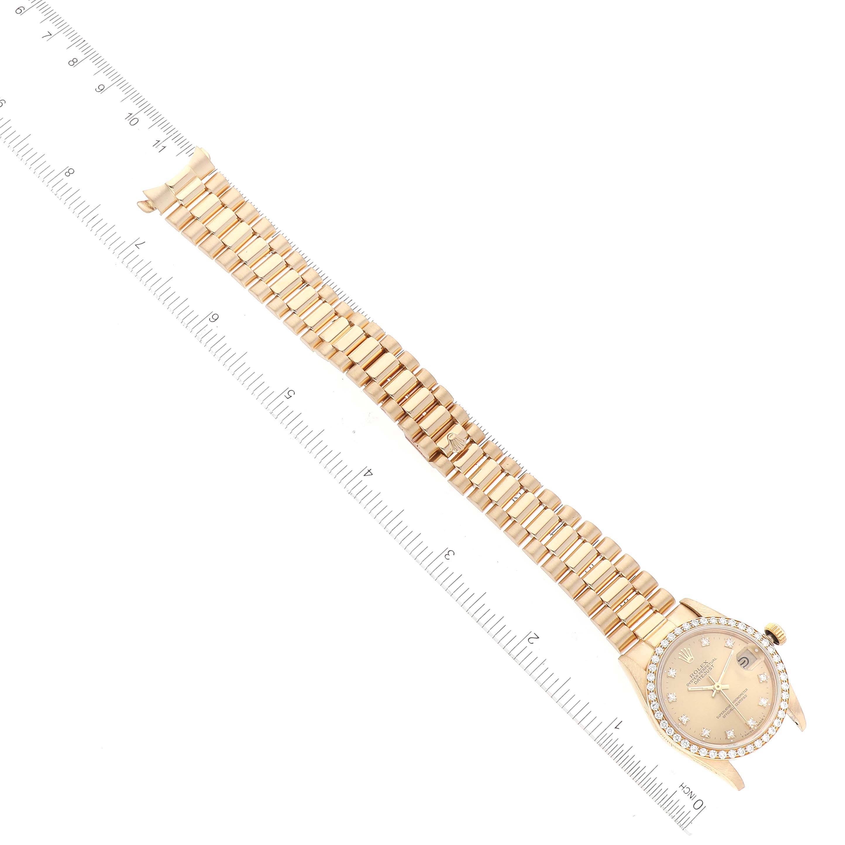 The Rolex President 68288 Women's Yellow Gold Champagne Dial 68288 Women's Yellow Gold Champagne Dial model watch is shown from an overhead angle, displaying the face and full band with a ruler for scale.