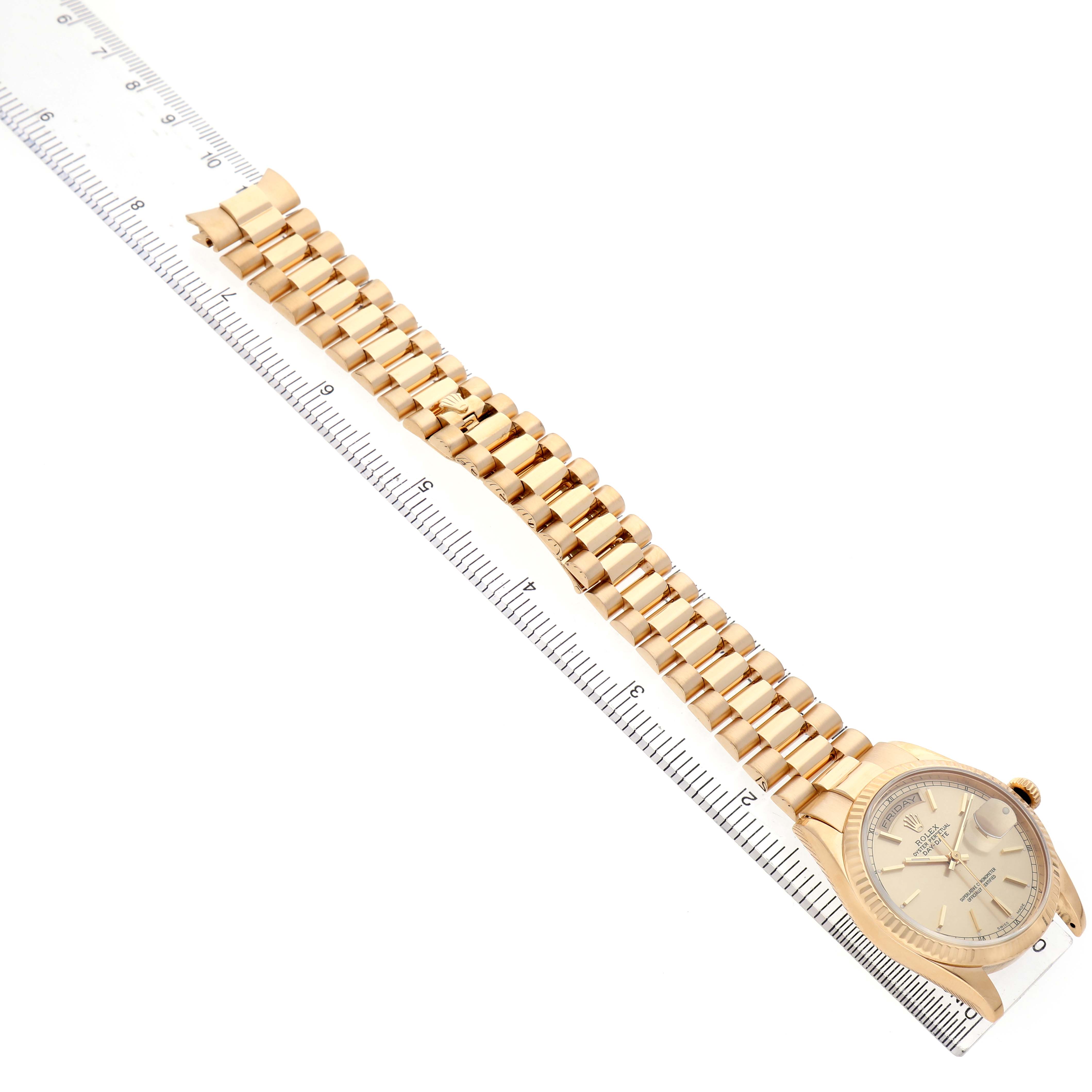 The Rolex President 118238 Men's Yellow Gold Champagne Dial model is shown at an angle highlighting the watch face and gold bracelet, alongside a ruler for scale.
