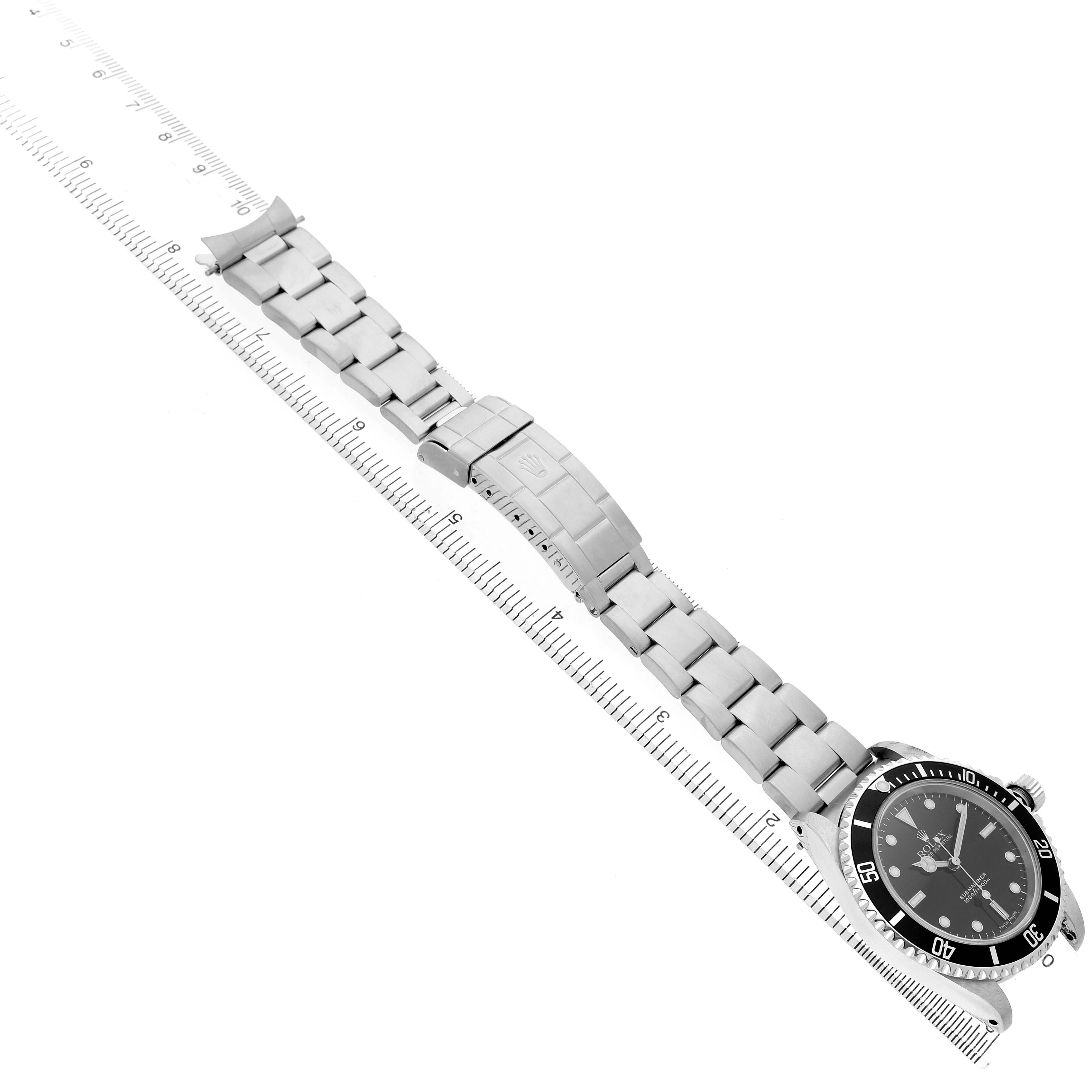 The Rolex Submariner 14060 Men's Stainless Steel Black Dial watch is shown from a three-quarter angle, highlighting the face, bracelet, and clasp alongside a ruler.