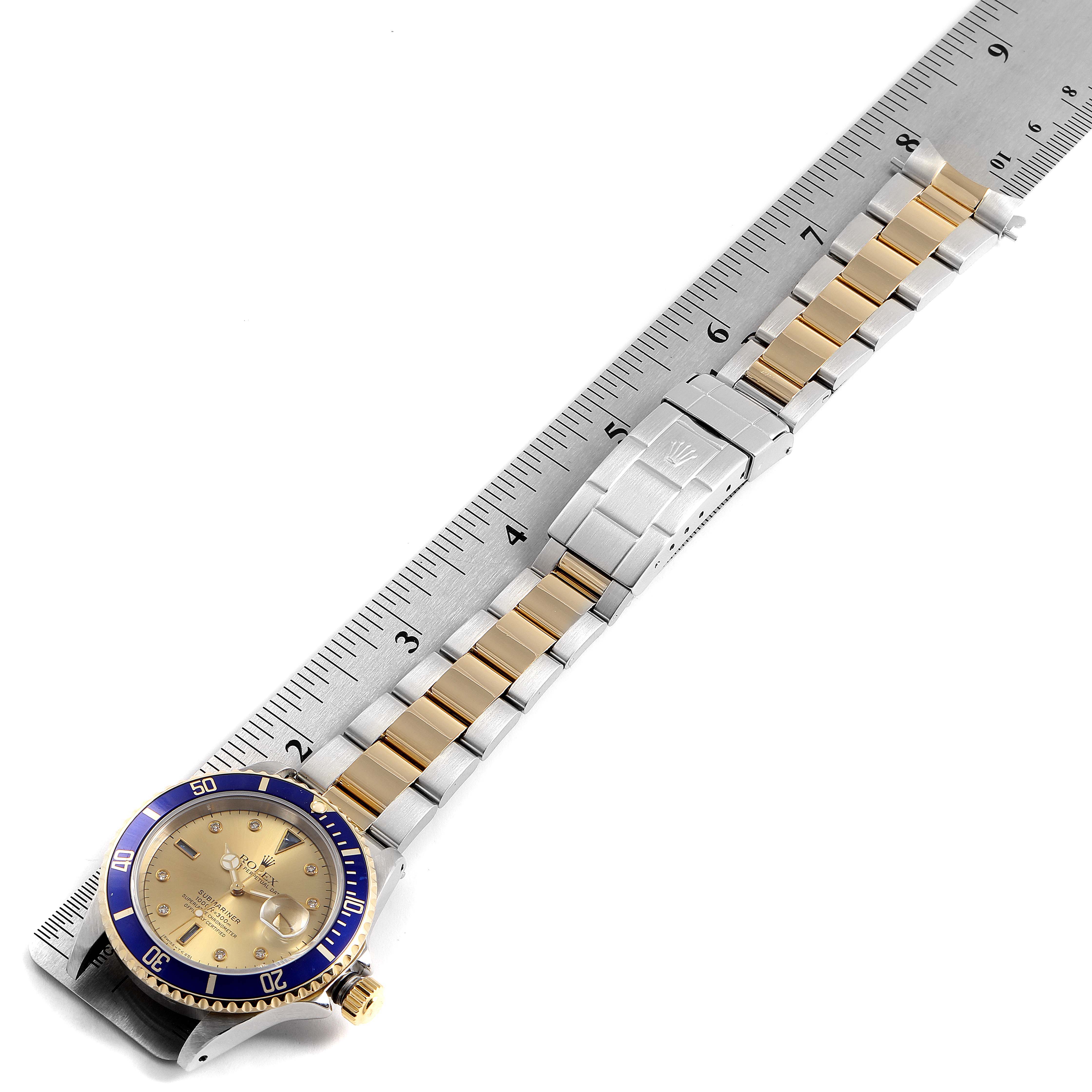 The image shows the face, bezel, and entire bracelet of a Rolex Submariner 16613 Men
s Steel and Gold (two tone) Champagne Dial 16613 Men
s Steel and Gold (two tone) Champagne Dial watch positioned against a ruler for measurement.
