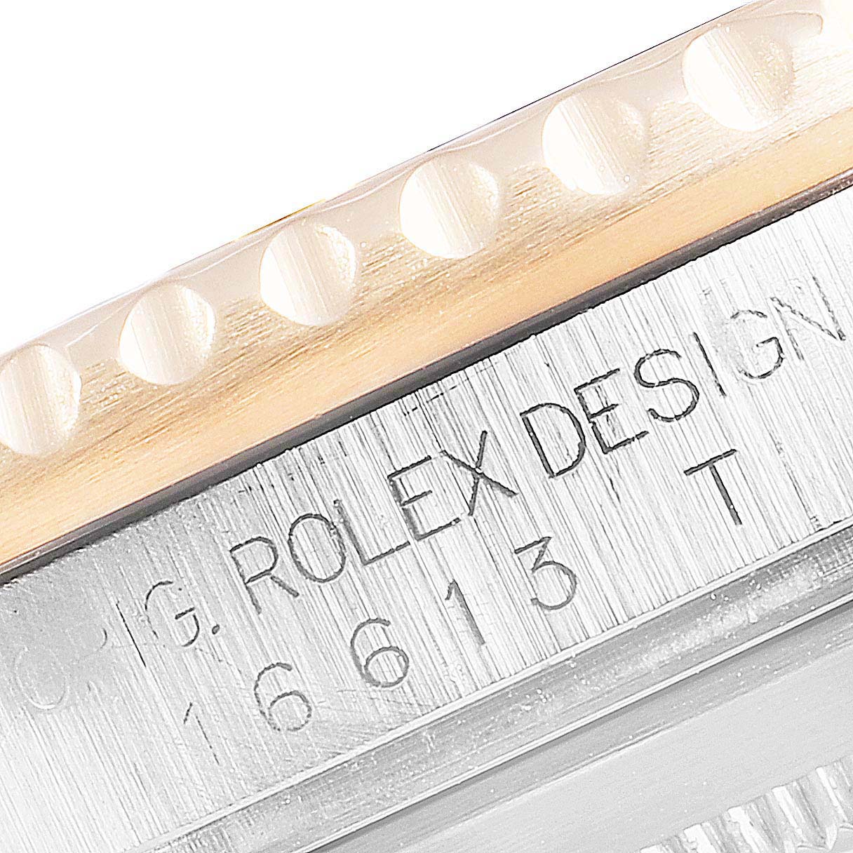 This close-up image shows the edge of the bezel and engraved text "ROLEX DESIGN" on the case of a Rolex Submariner 16613 Men's Steel and Gold (two tone) Grey Dial 16613 Men's Steel and Gold (two tone) Grey Dial watch.