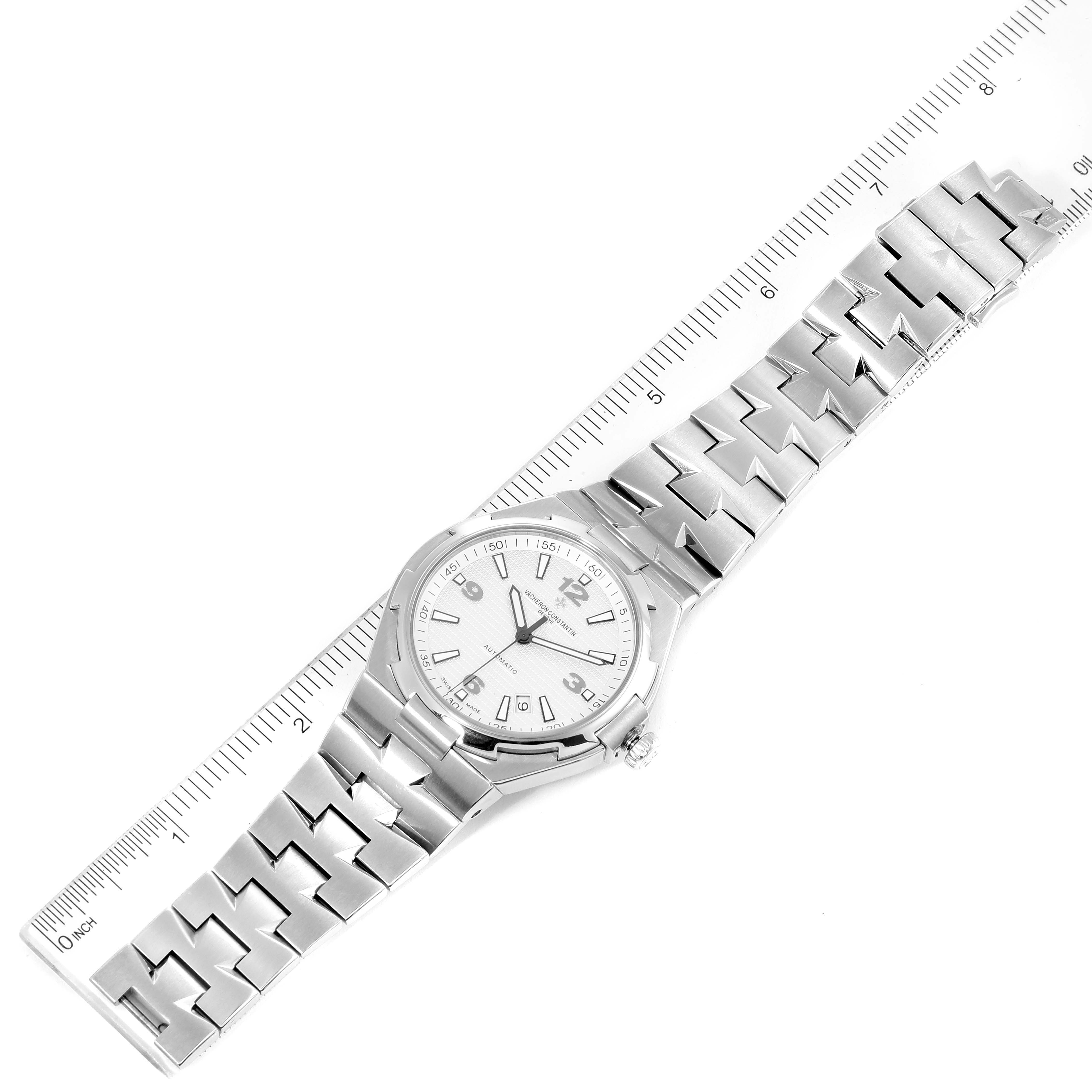 The Vacheron Constantin Overseas 47040B01A-9093 Men's Stainless Steel Silver Dial 47040B01A-9093 Men's Stainless Steel Silver Dial watch is shown from a top-down angle alongside a ruler, displaying the full bracelet and face.