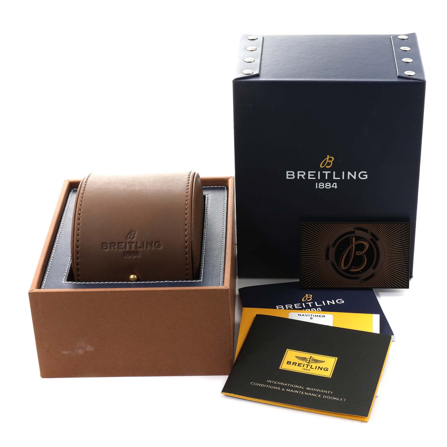 The image shows the packaging and accessories of a Breitling Navitimer watch, including a brown watch case, outer box, and warranty booklet.