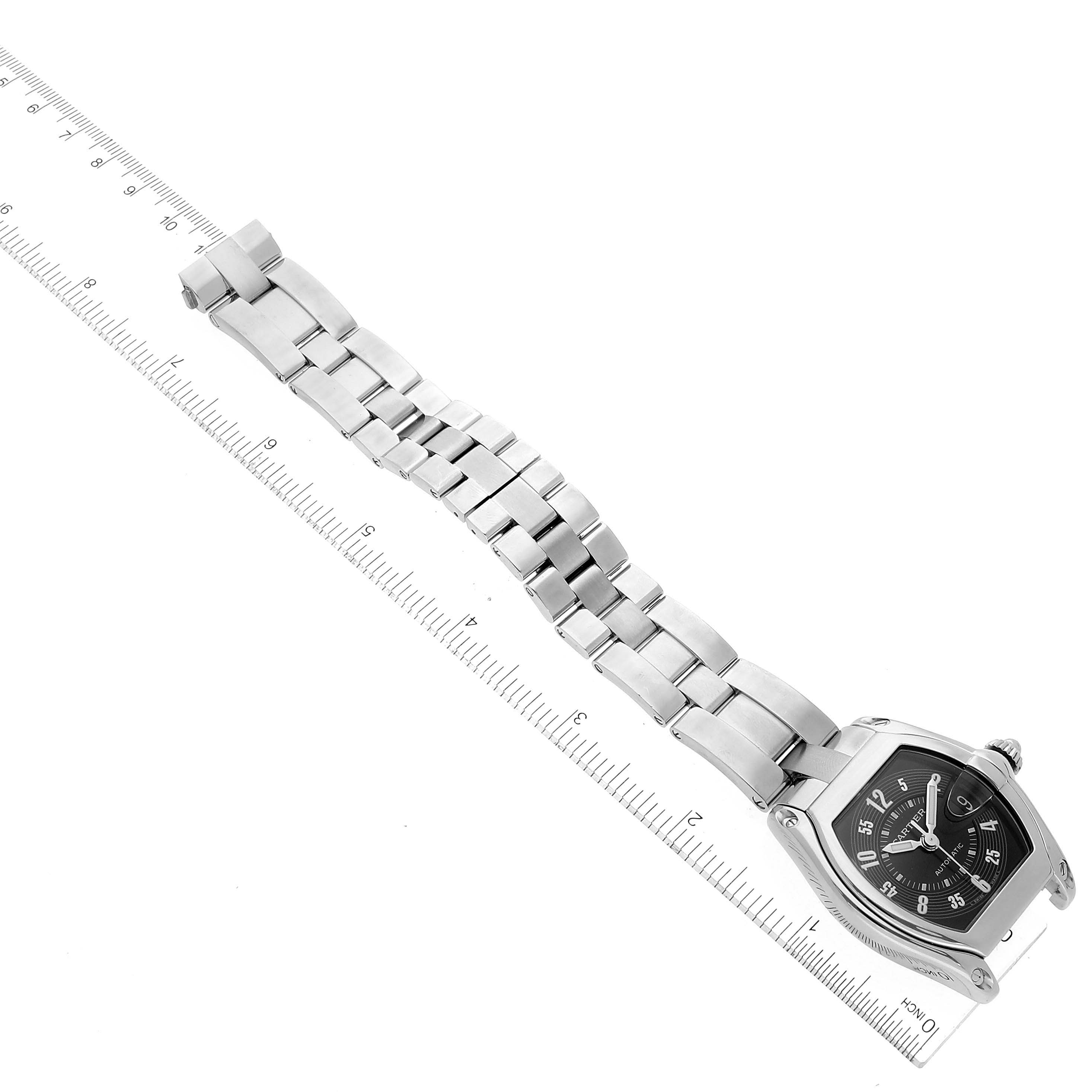 The image shows a Cartier Roadster W62004V3 Men's Stainless Steel Black Dial W62004V3 Men's Stainless Steel Black Dial watch laid flat next to a ruler, highlighting its band and face.