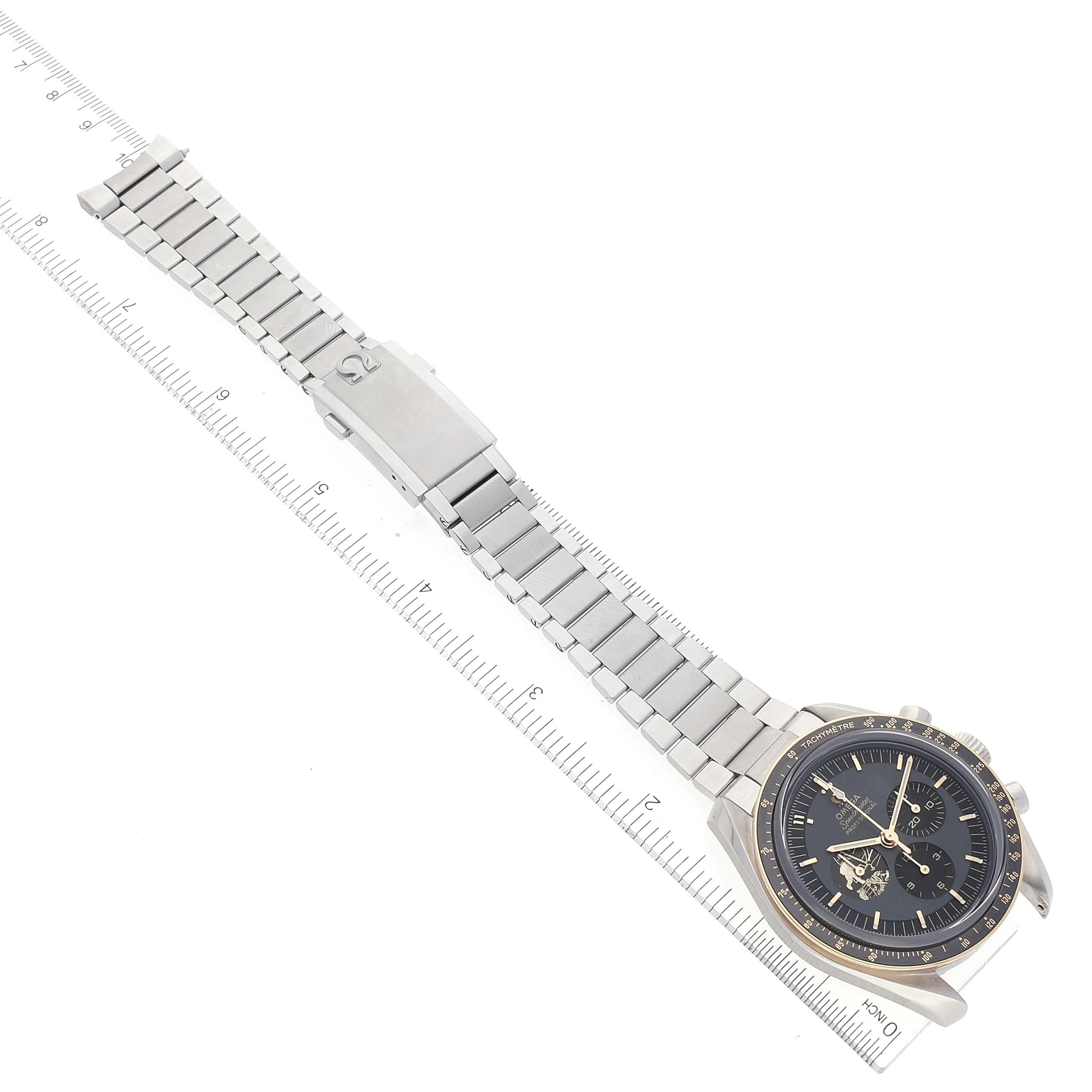 The image shows an Omega Speedmaster 310.20.42.50.01.001 Men's Stainless Steel Grey Dial 310.20.42.50.01.001 Men's Stainless Steel Grey Dial watch laid flat with its metal band extended, viewed from above, alongside a ruler.