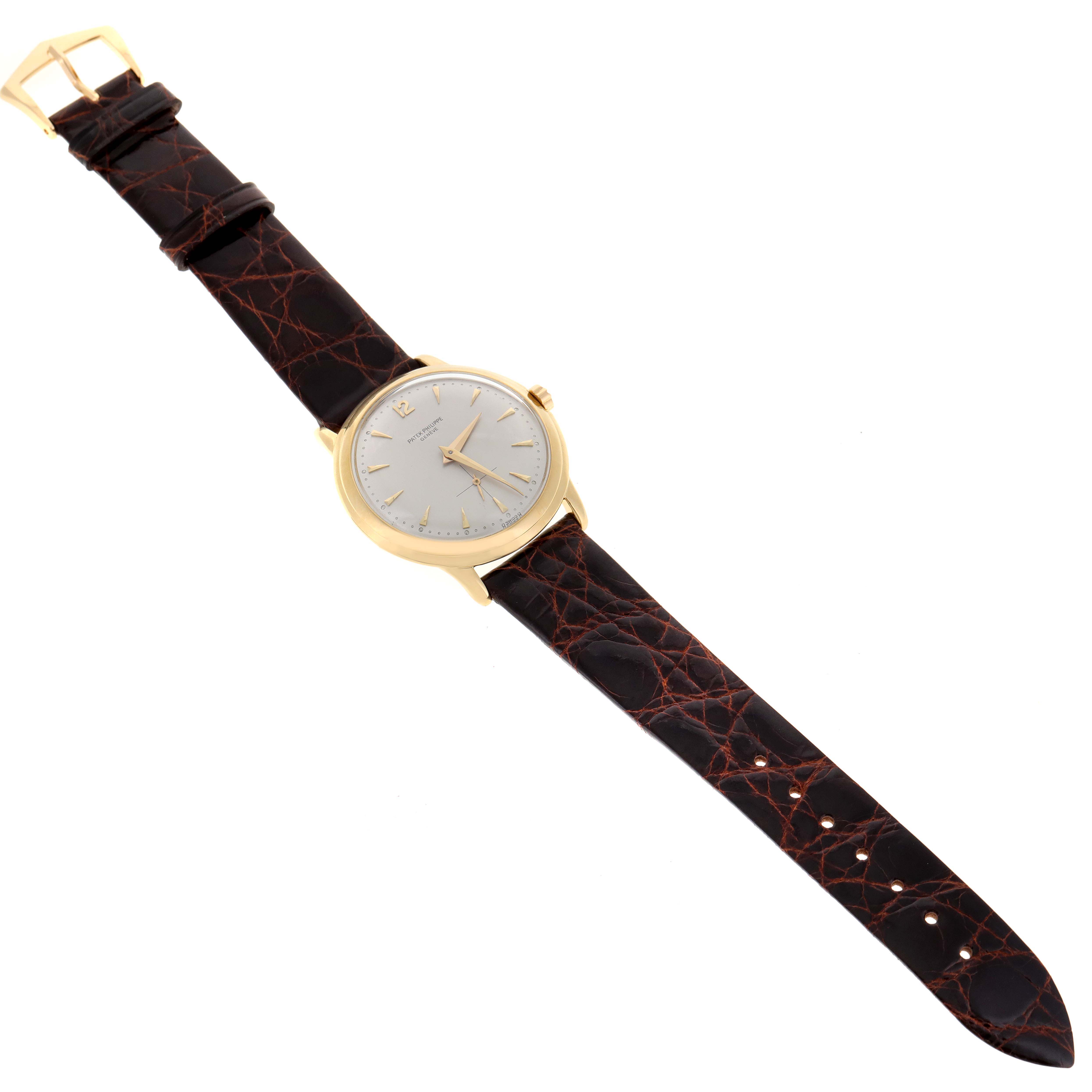 The image shows a vintage Patek Philippe watch from a top-down angle, displaying its entire face, leather strap, and buckle.