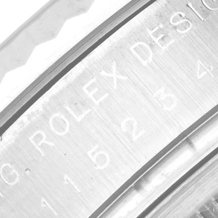 This close-up image shows the engraved side of the case of a Rolex Date 115234 Men's Stainless Steel Silver Dial 115234 Men's Stainless Steel Silver Dial model watch.