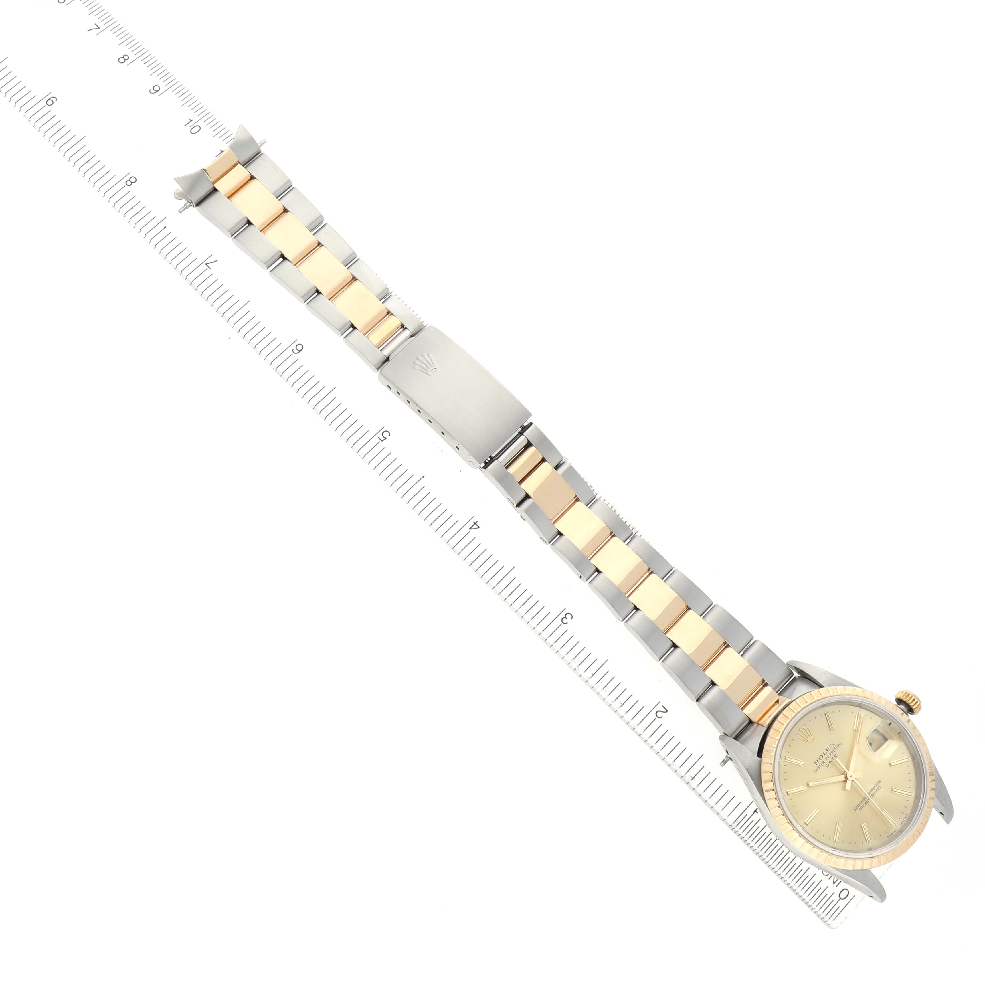 The Rolex Date 15223 Men's Steel and Gold (two tone) Champagne Dial watch is shown from a top-down angle, with the full bracelet and clasp visible alongside a ruler for scale.