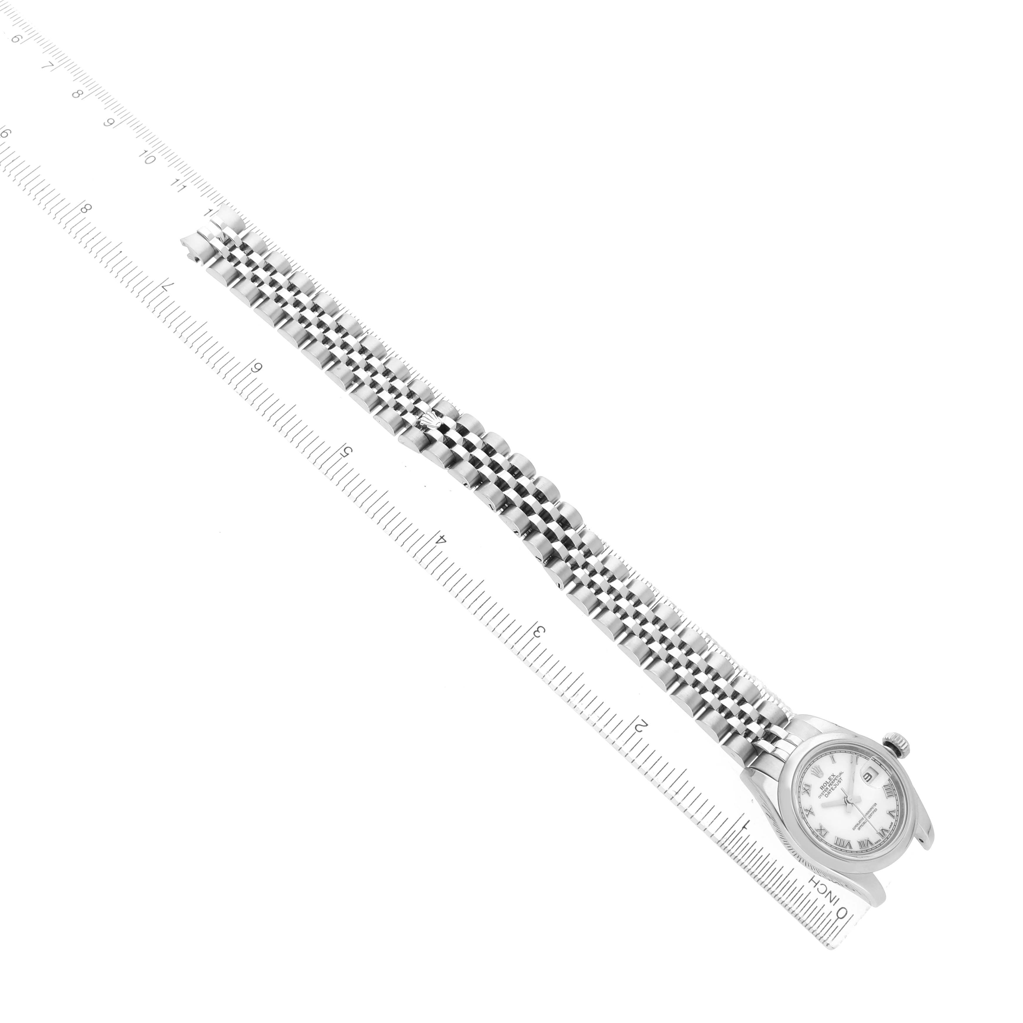 The Rolex Datejust 179160 Women's Stainless Steel White Dial watch is shown from a top-down angle, displaying its full bracelet and face next to a ruler for scale.