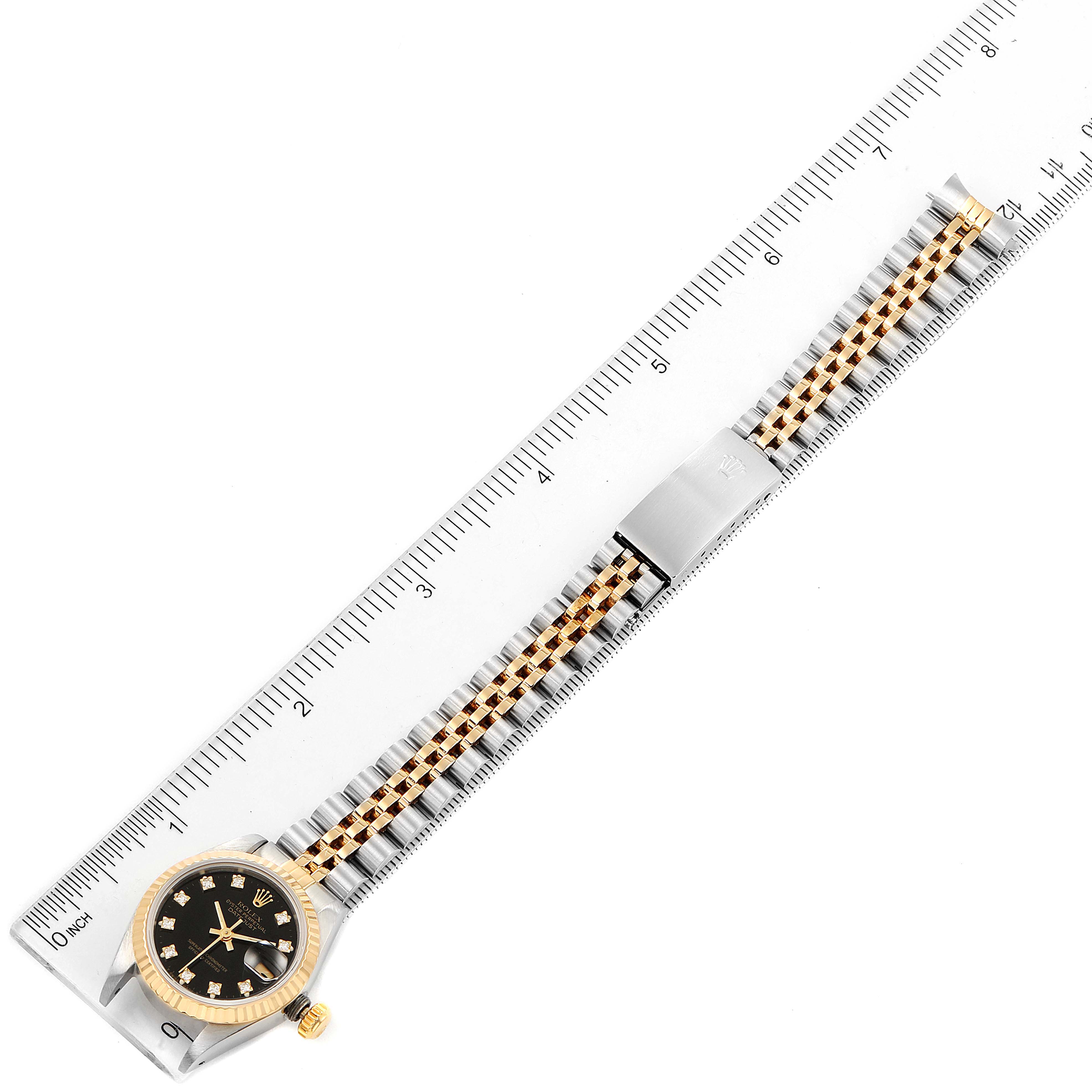 The image shows a Rolex Datejust 69173 Women
s Steel and Gold (two tone) Black Dial 69173 Women
s Steel and Gold (two tone) Black Dial watch from a top-down angle with a ruler for scale.